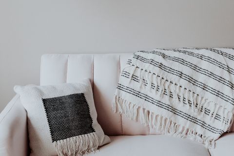 Weißes Sofa mit dekorativem Kissen und gestreifter Decke.