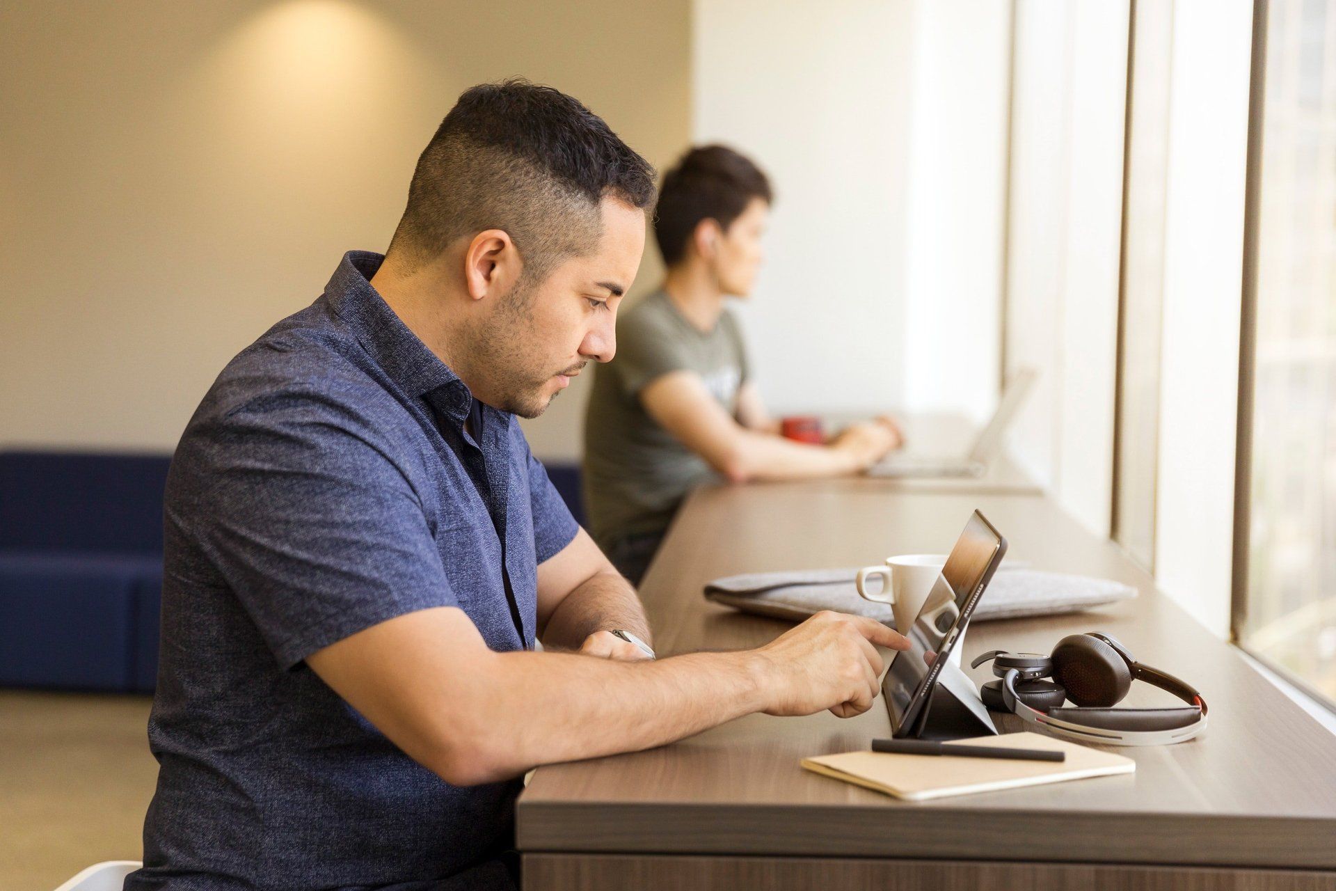 A man is sitting at a table using a tablet