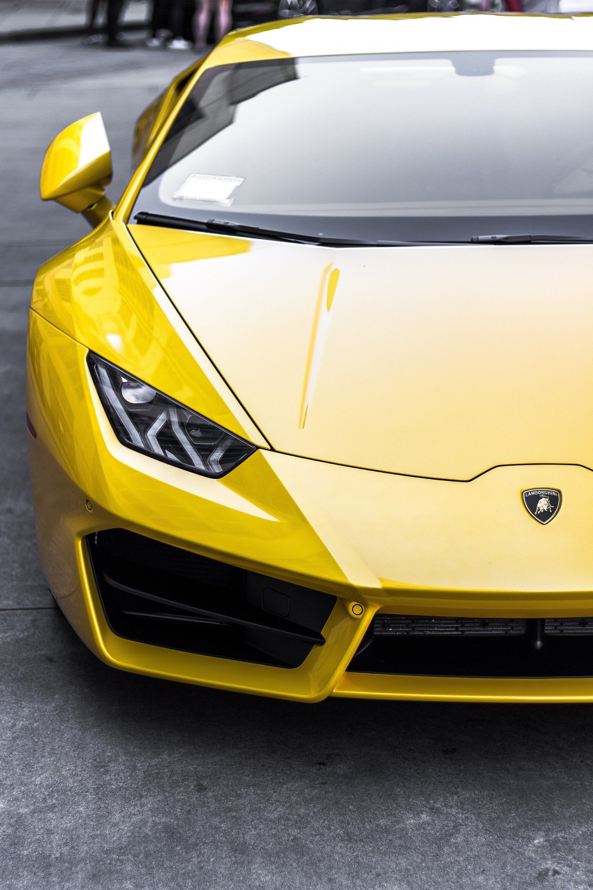 Yellow Lamborghini sports car parked on a gray street.