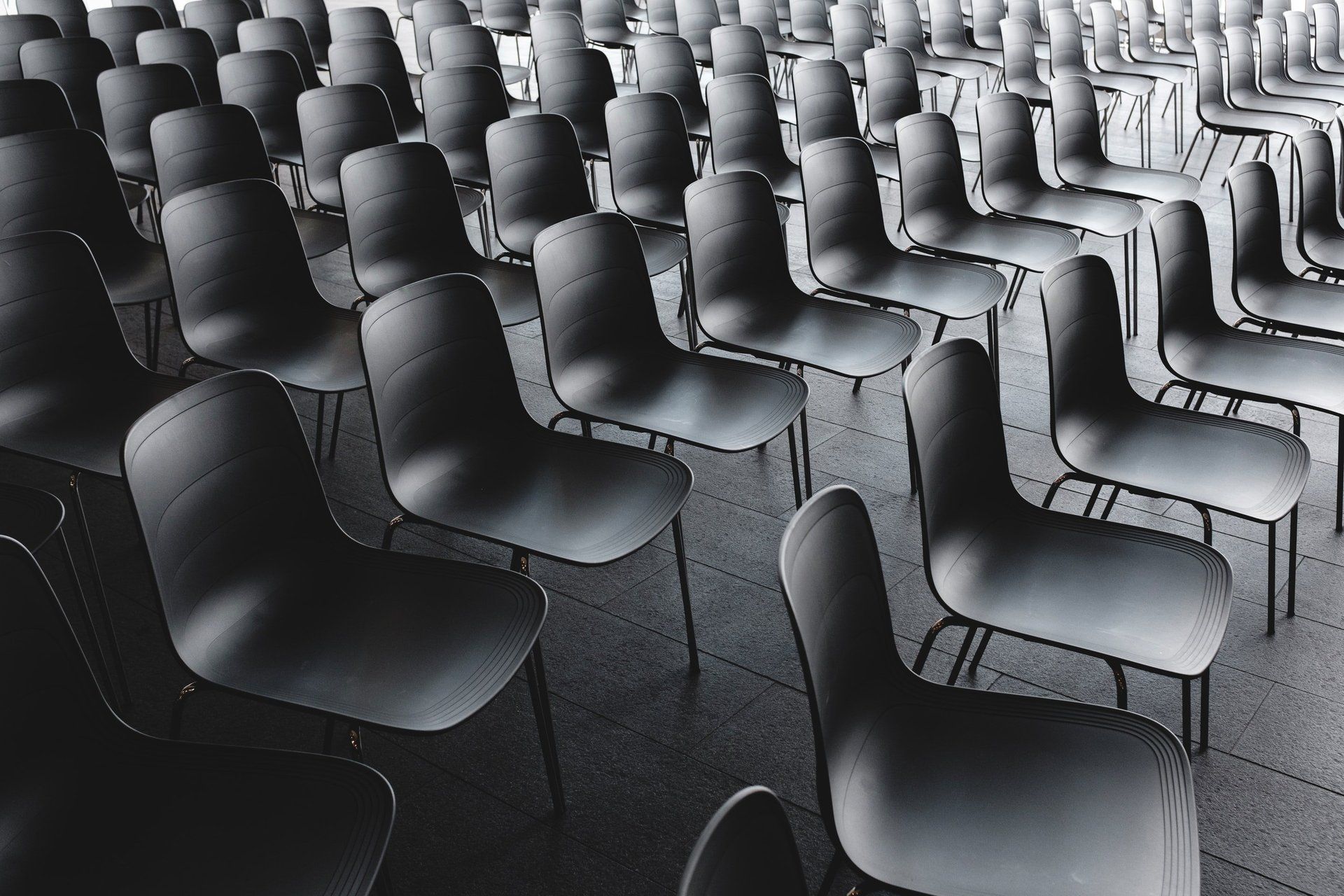 Rows of black chairs are lined up in a room.