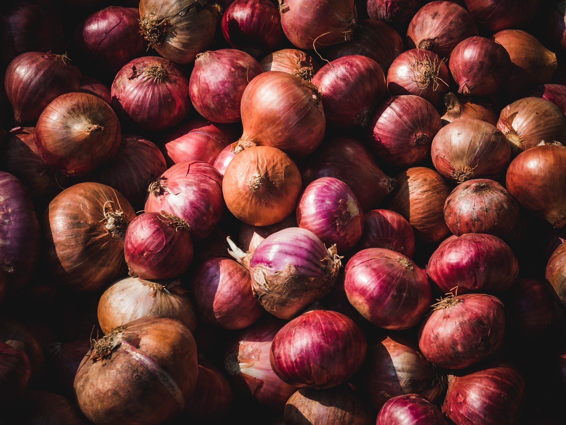 A pile of red onions sitting on top of each other on a table.