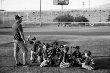 A man is standing next to a group of young baseball players on a field.