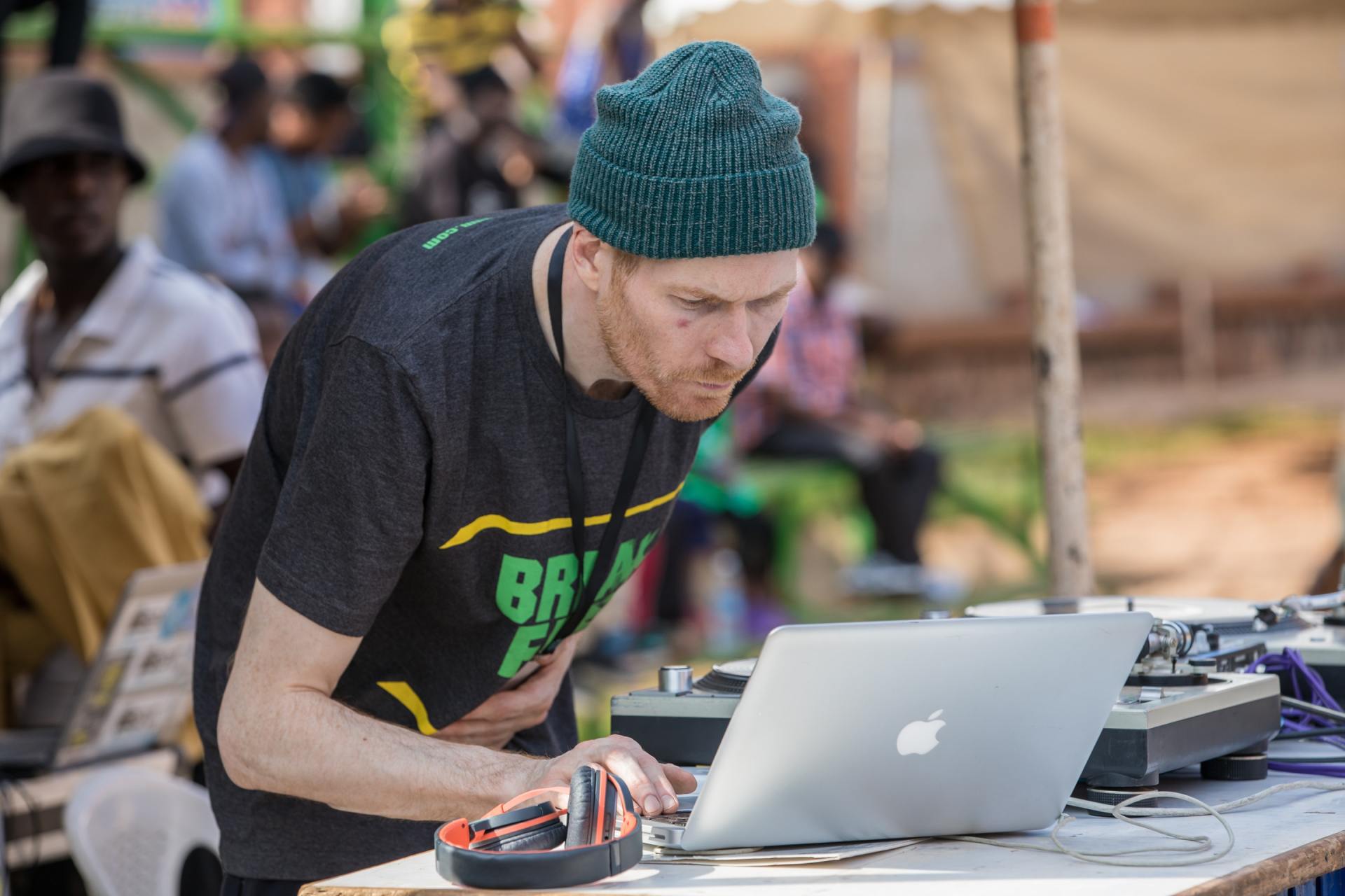 A man wearing a beanie is using an apple laptop.