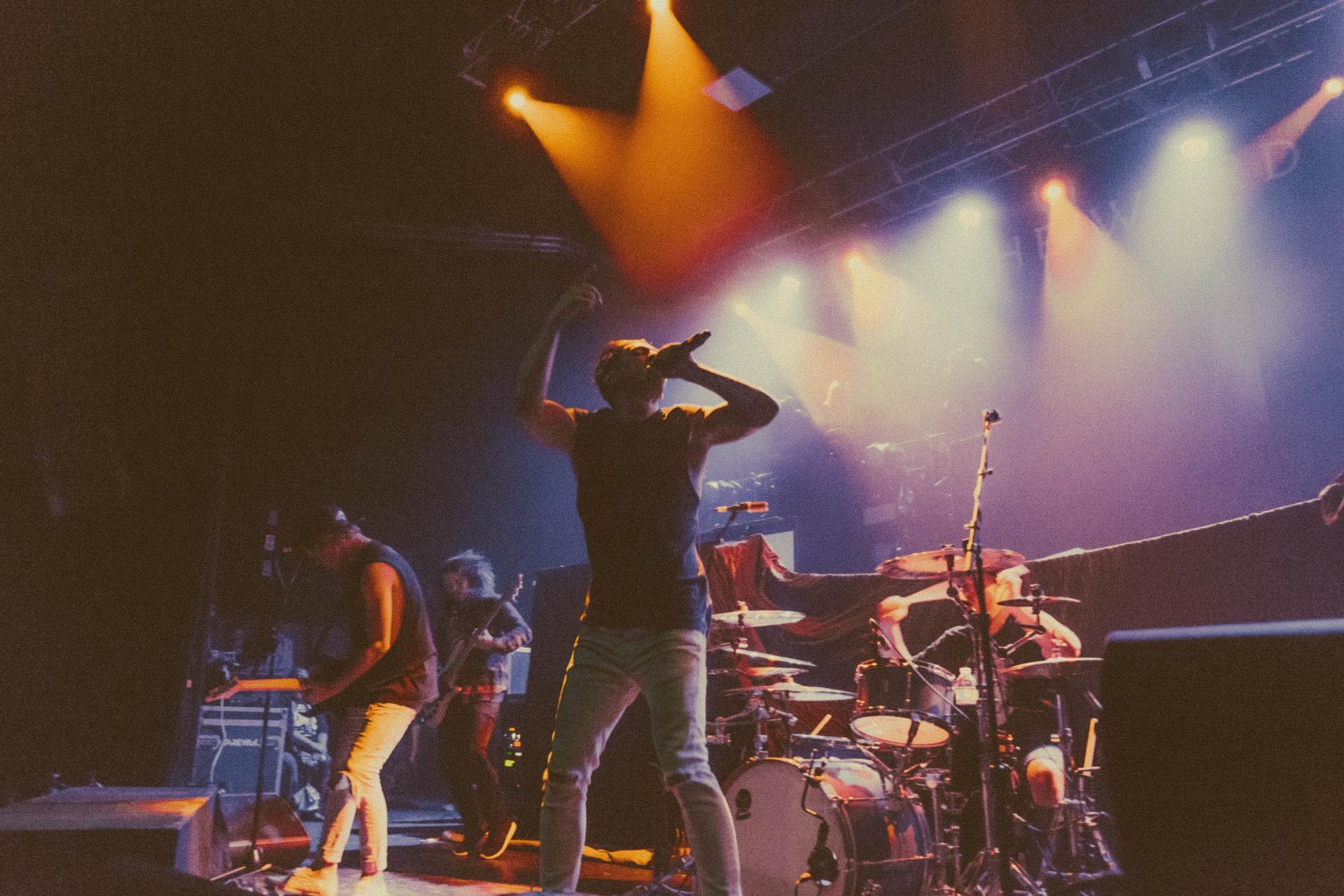 Concert stage with musicians performing under colorful spotlights and haze