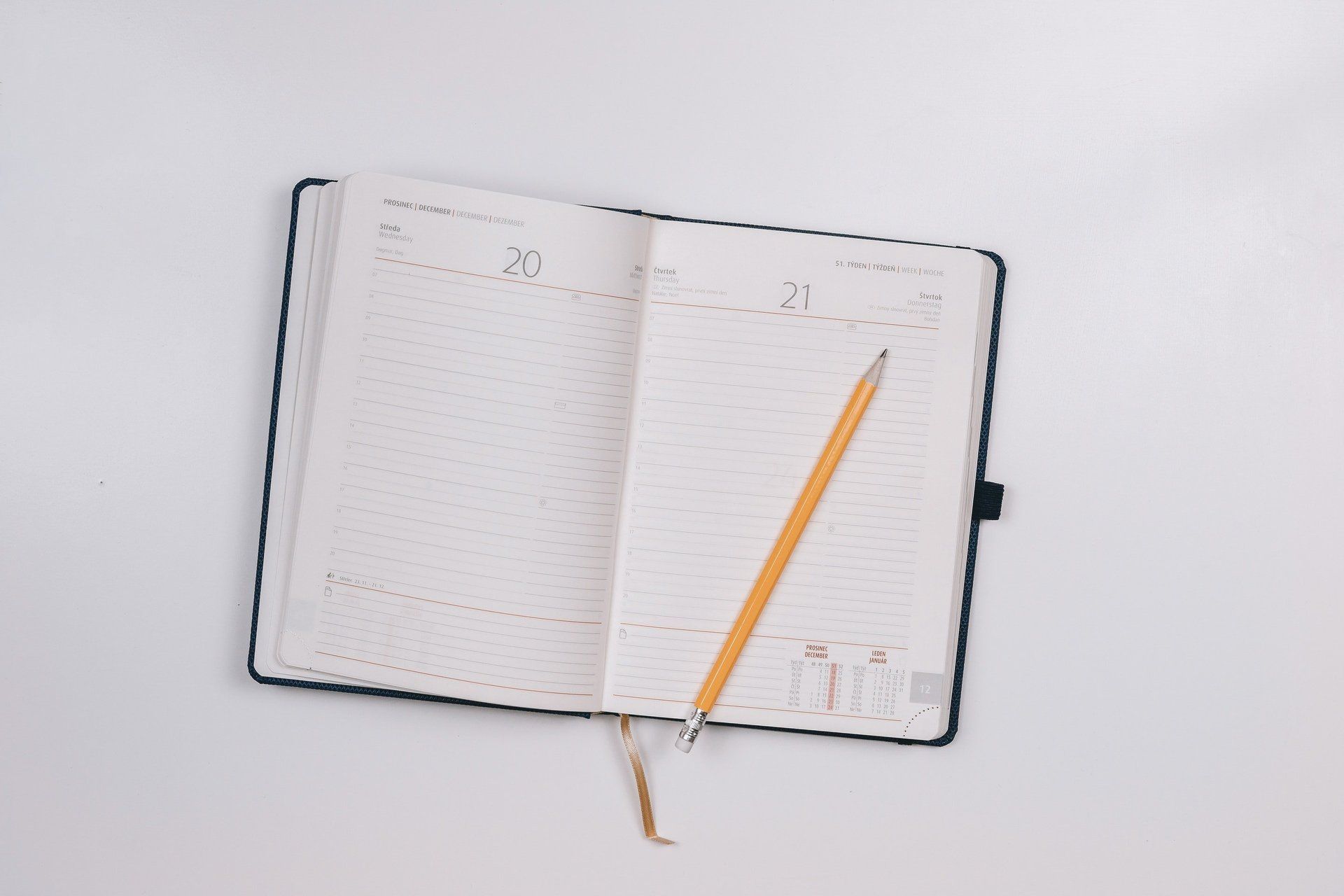 An open notebook with a pencil in it on a white surface.