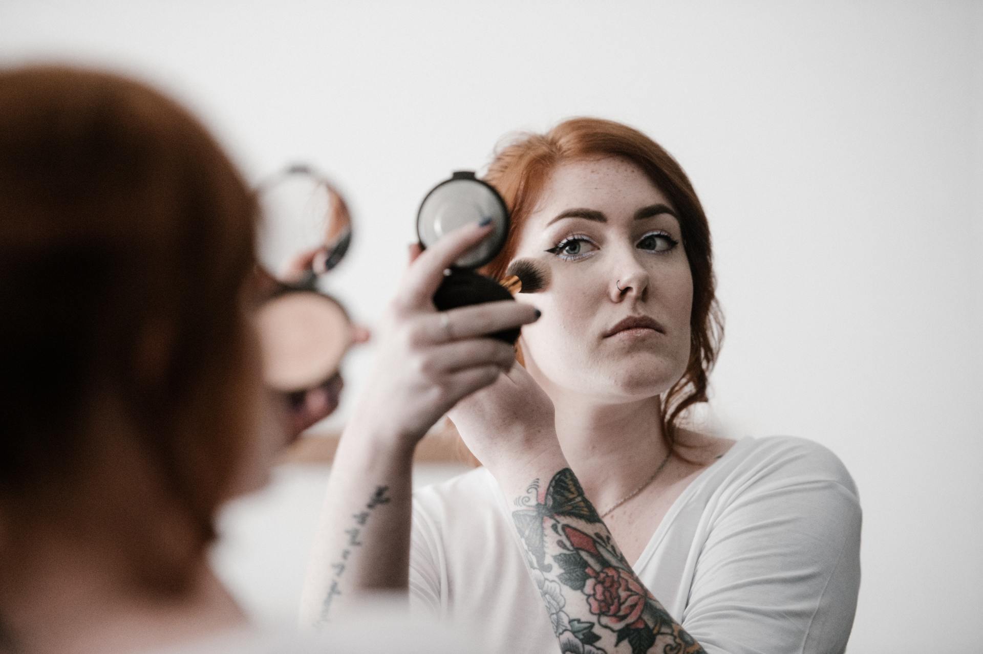 A woman is applying makeup in front of a mirror.
