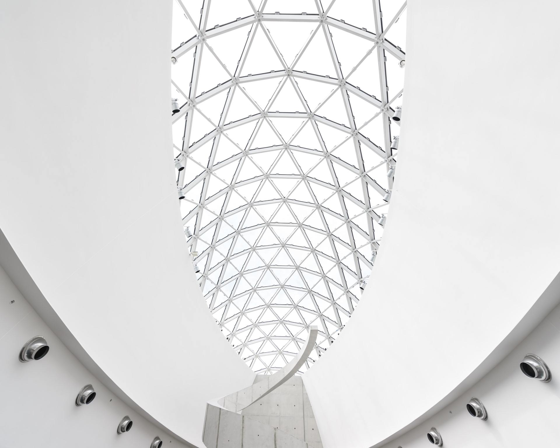 White interior with a triangular glass ceiling, arched walls, and modern architecture.