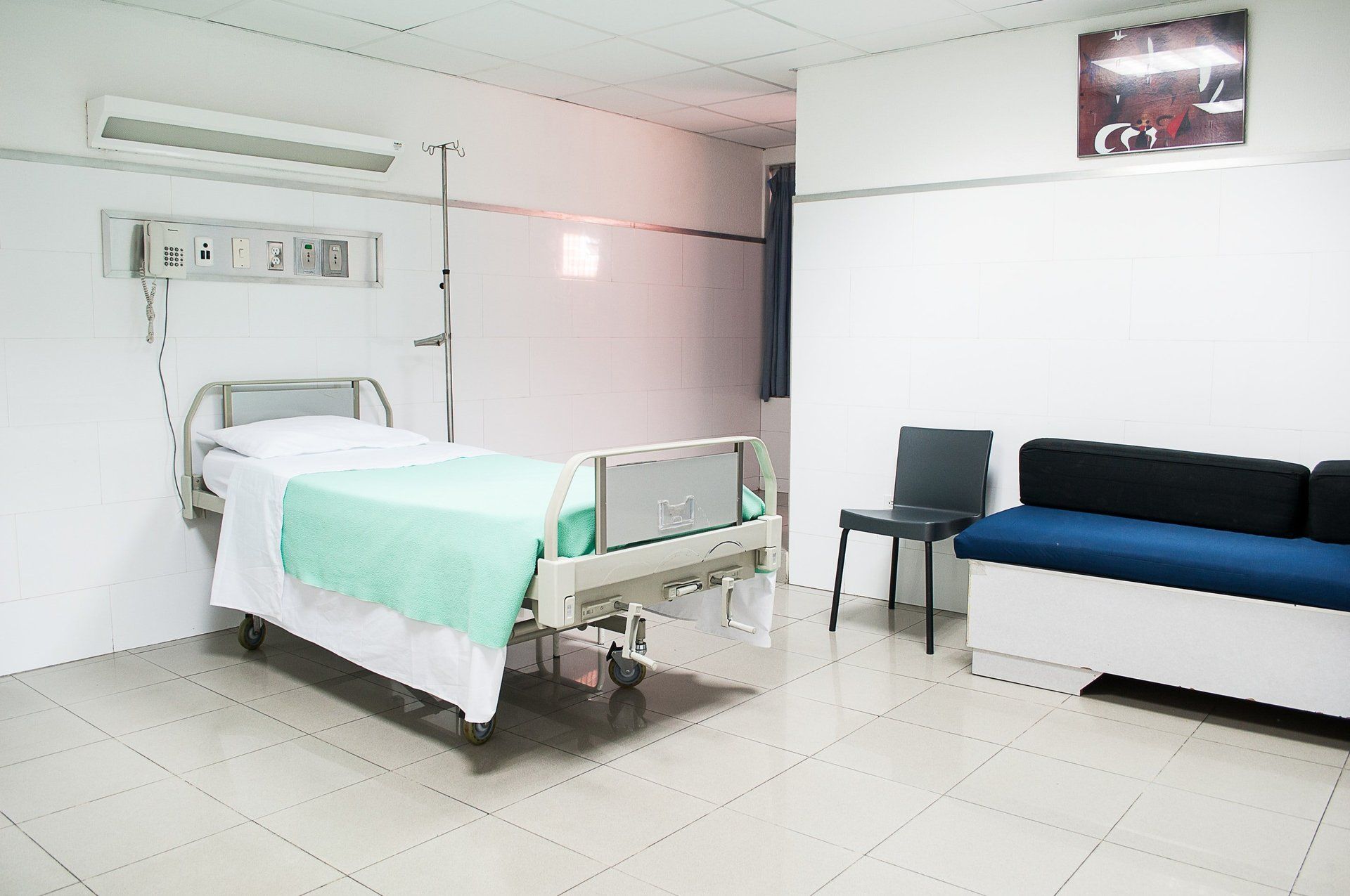 An empty hospital room with a bed and a couch.