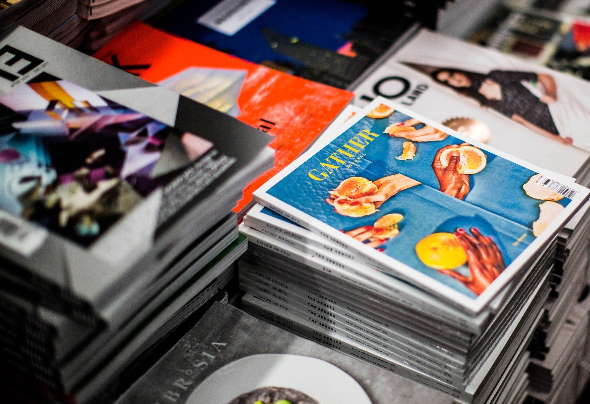 Stacks of colorful magazines, covers featuring photography and text.