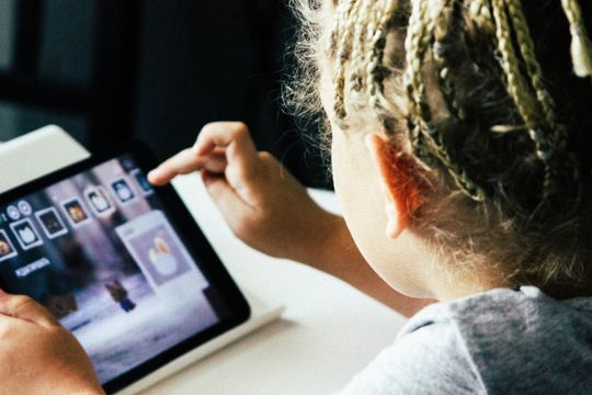 Een jong meisje speelt een spel op een tablet.