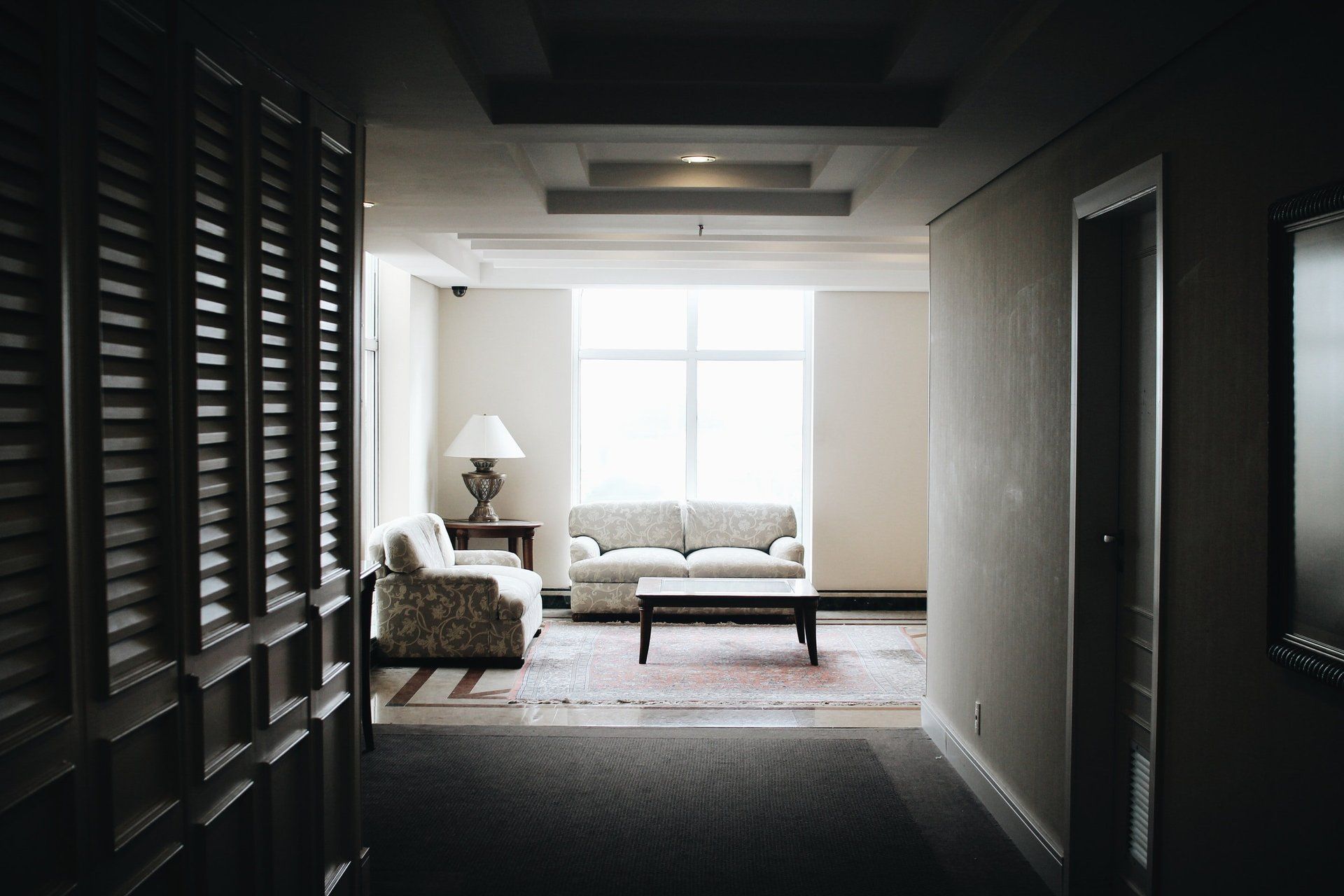 A hallway leading to a living room with a couch and a table