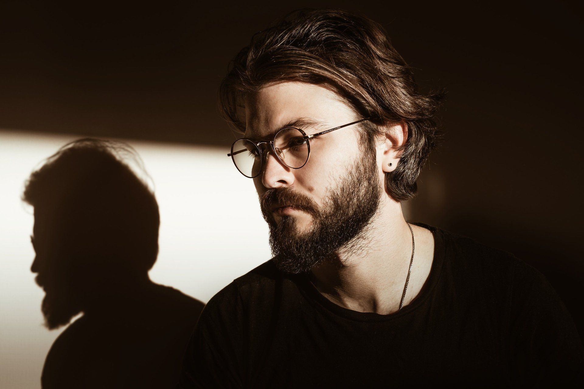 A man with glasses and a beard is looking thoughtful.