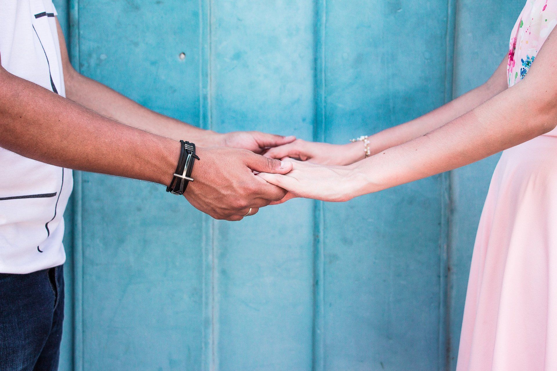 A man and a woman are holding hands in front of a blue door.