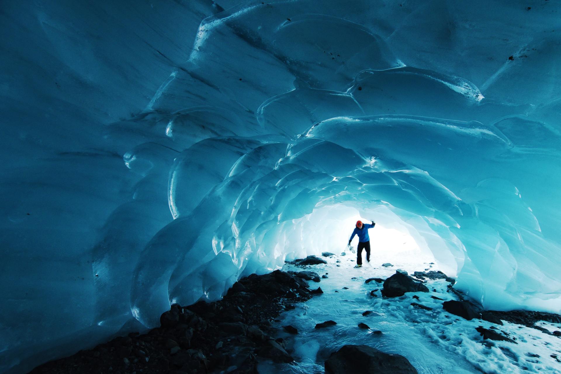 A man is standing in the middle of an ice cave.