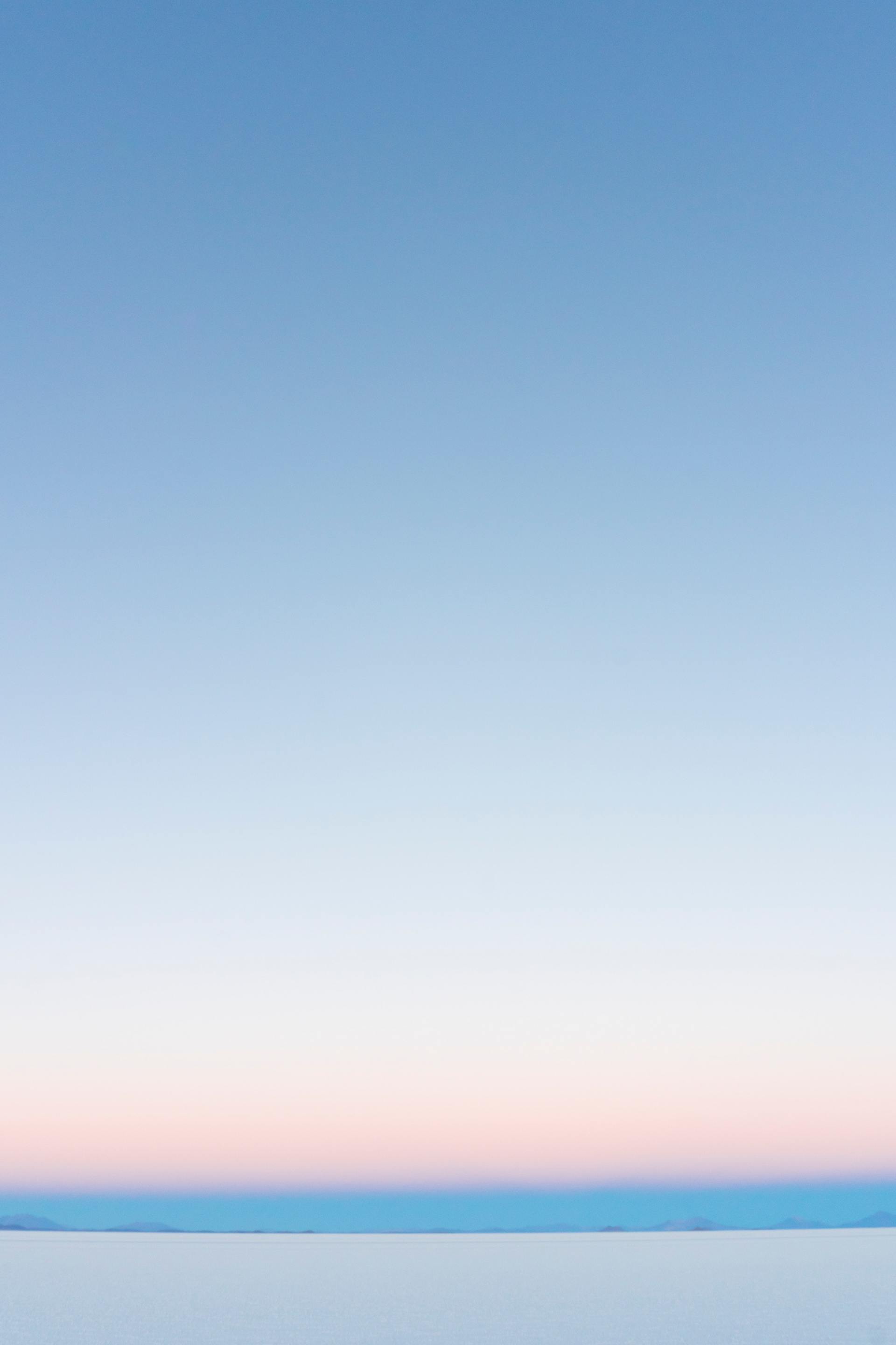Pale blue sky over a strip of pink and blue horizon, and a white ground.