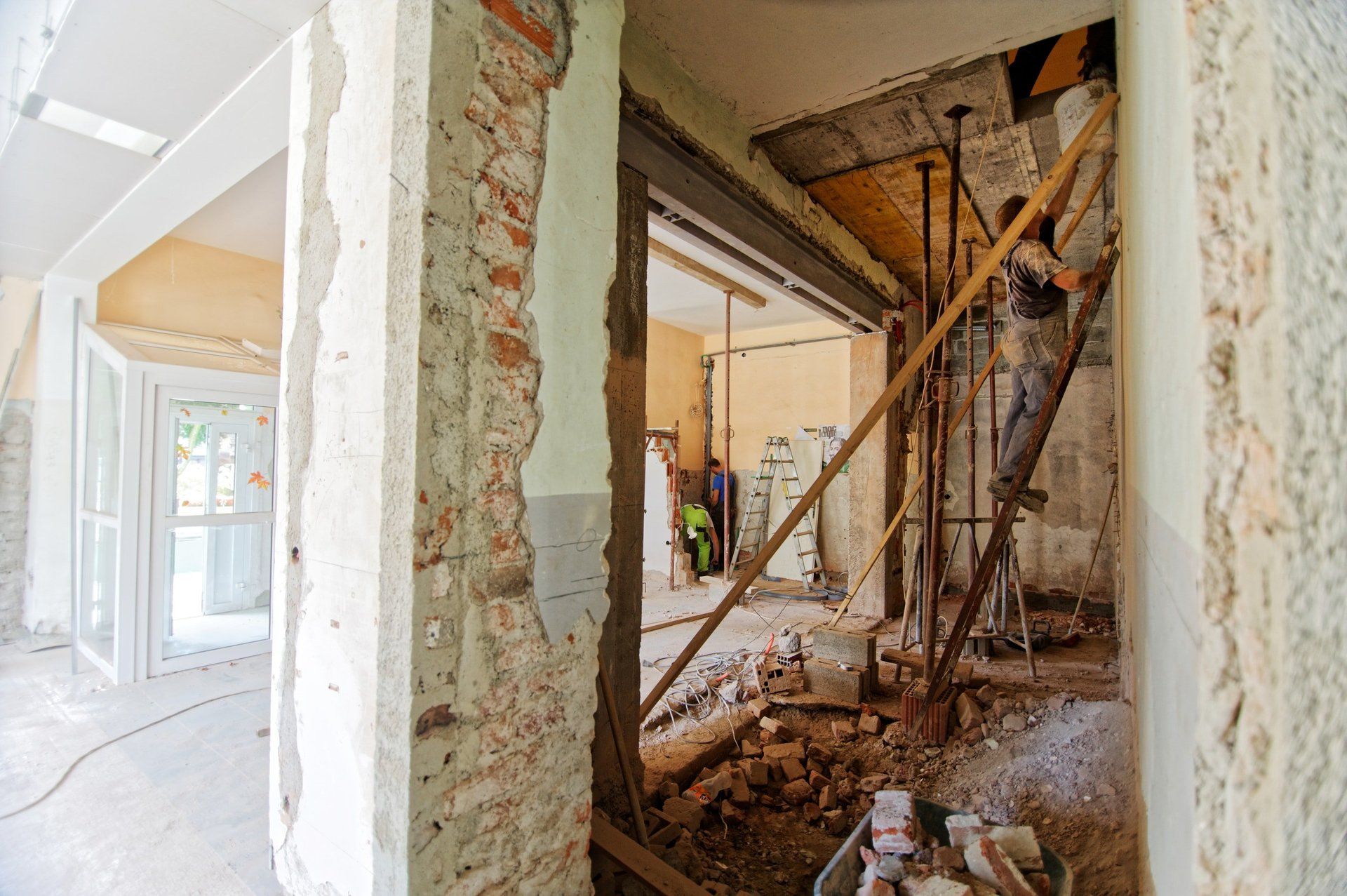 A man is standing on a ladder in a building under construction.