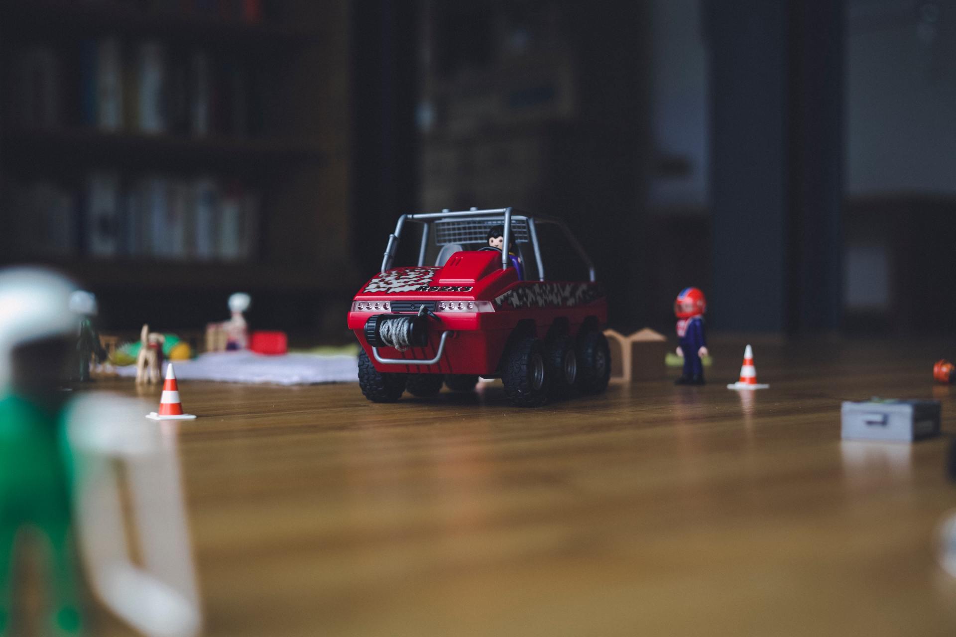 A red toy car is sitting on top of a wooden table.