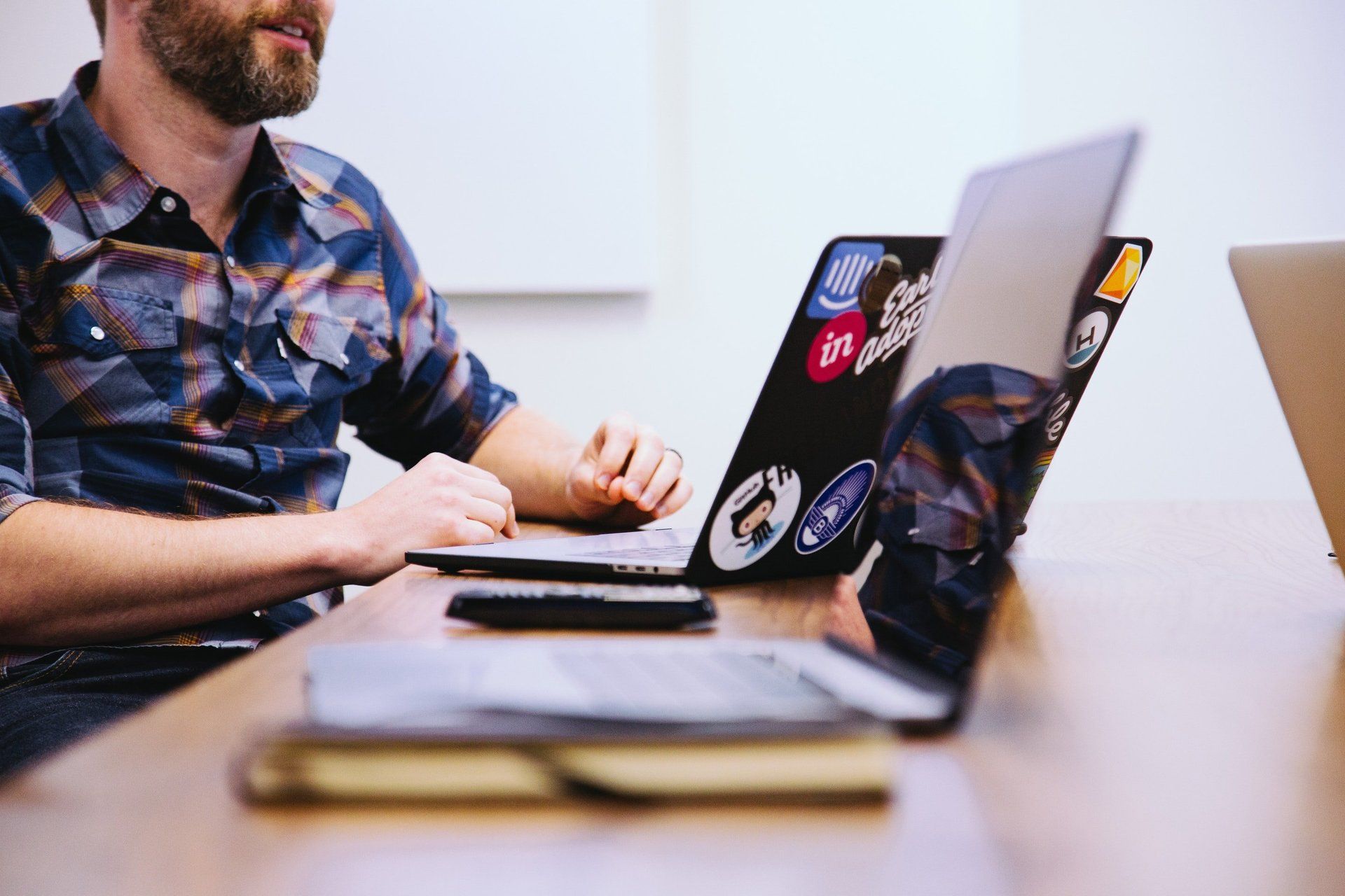 A man is sitting at a table using a laptop computer.