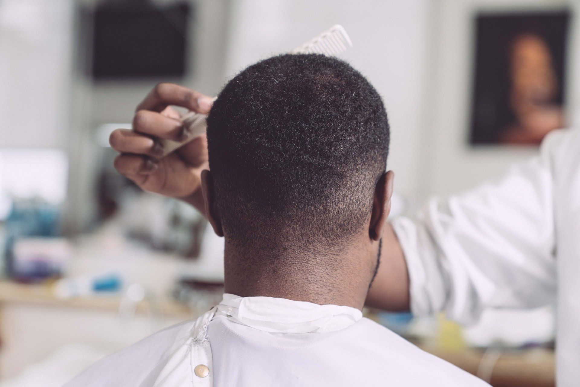 A man is getting his hair cut by a barber in a barber shop.