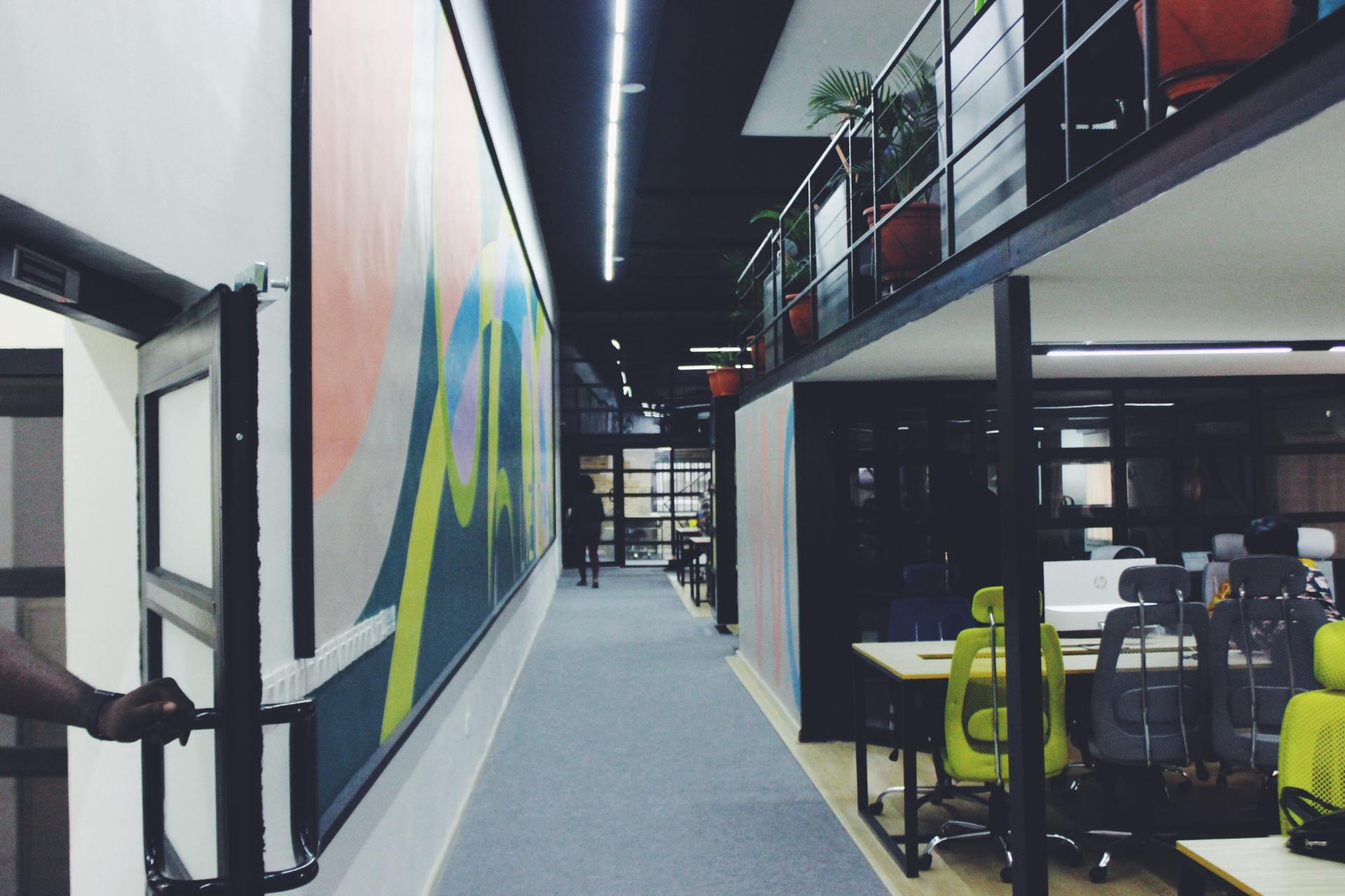 A long hallway in an office building with tables and chairs.