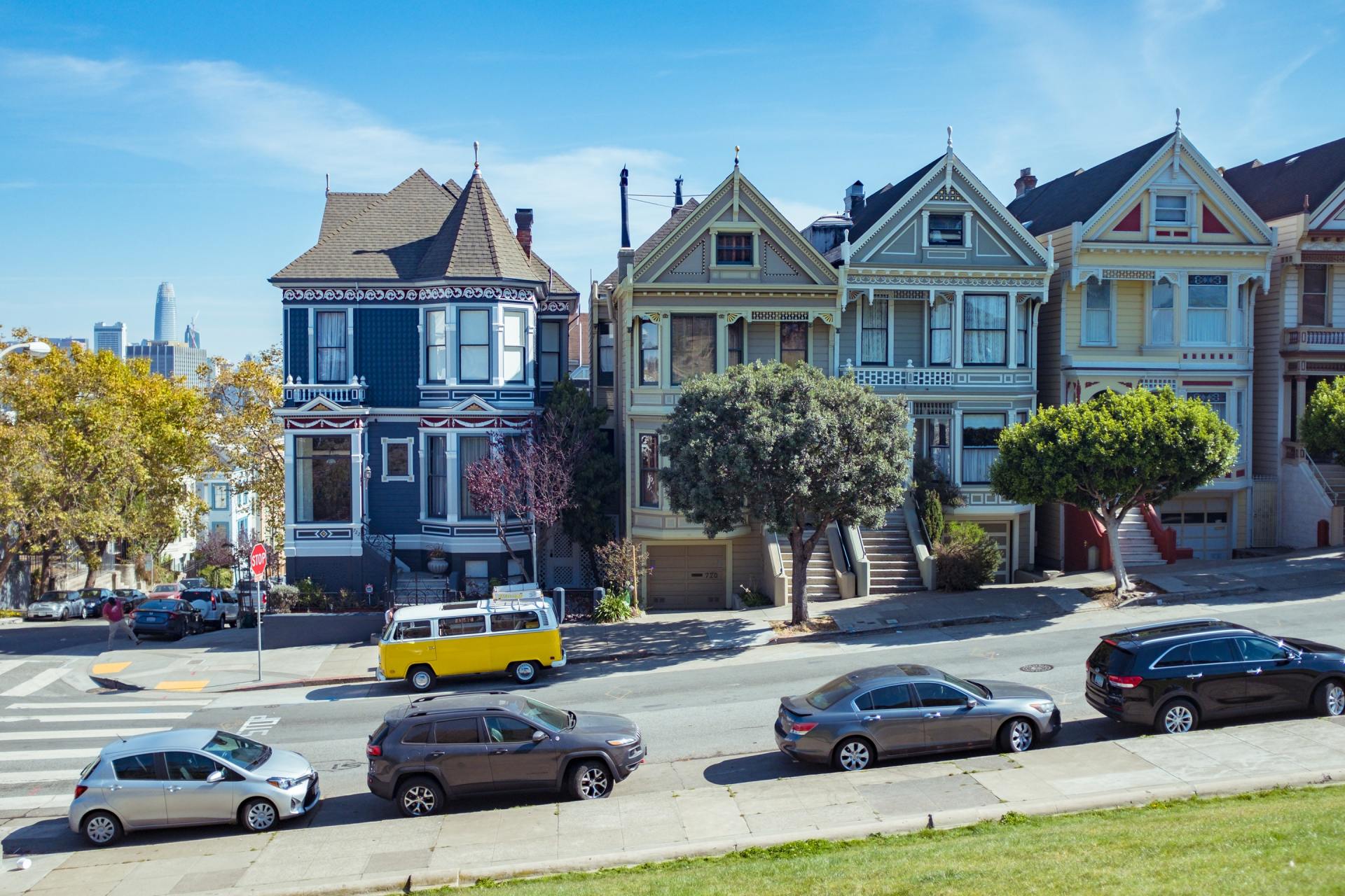 a row of houses with cars parked on the side of the road .