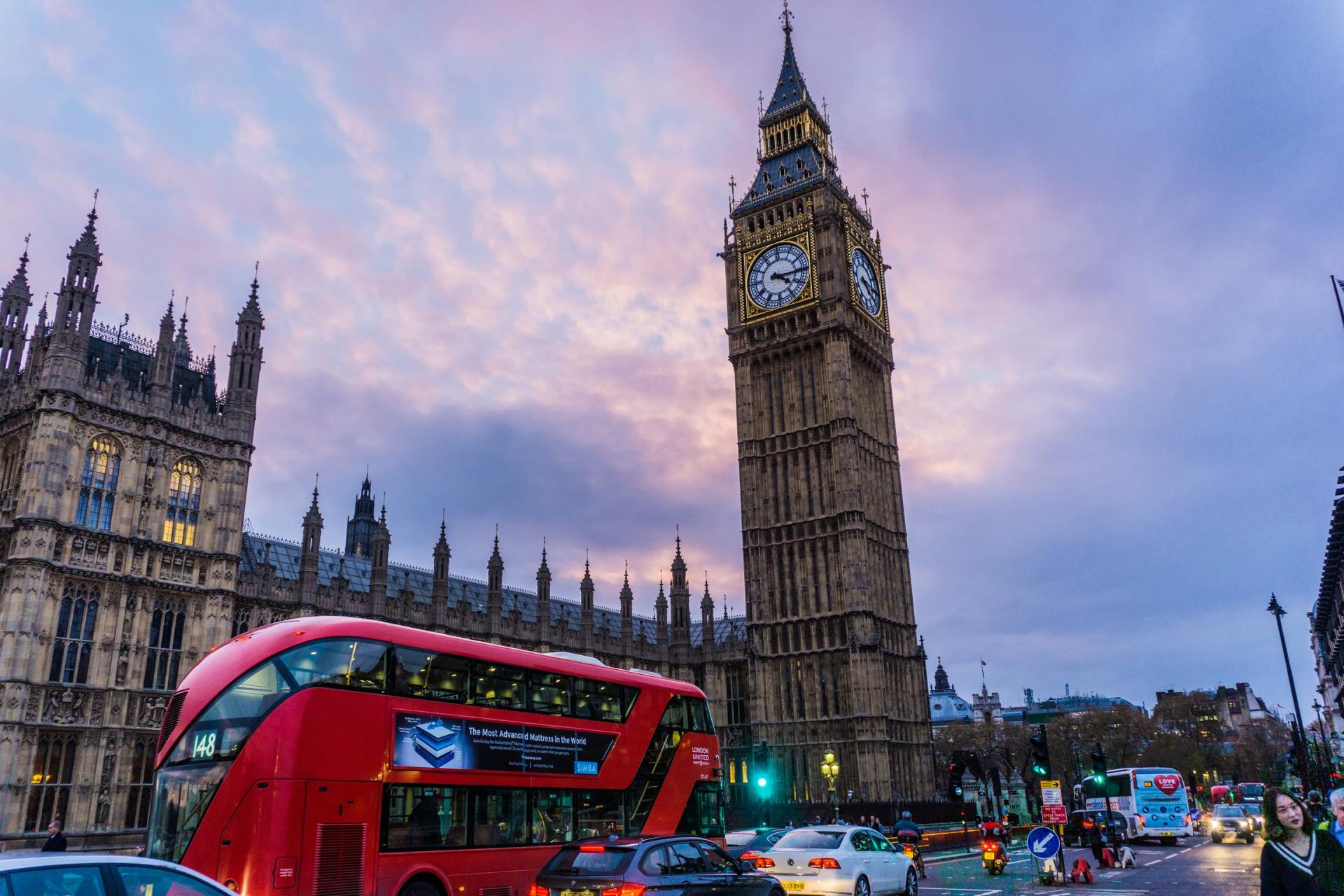 A double decker bus is driving past big ben in london.