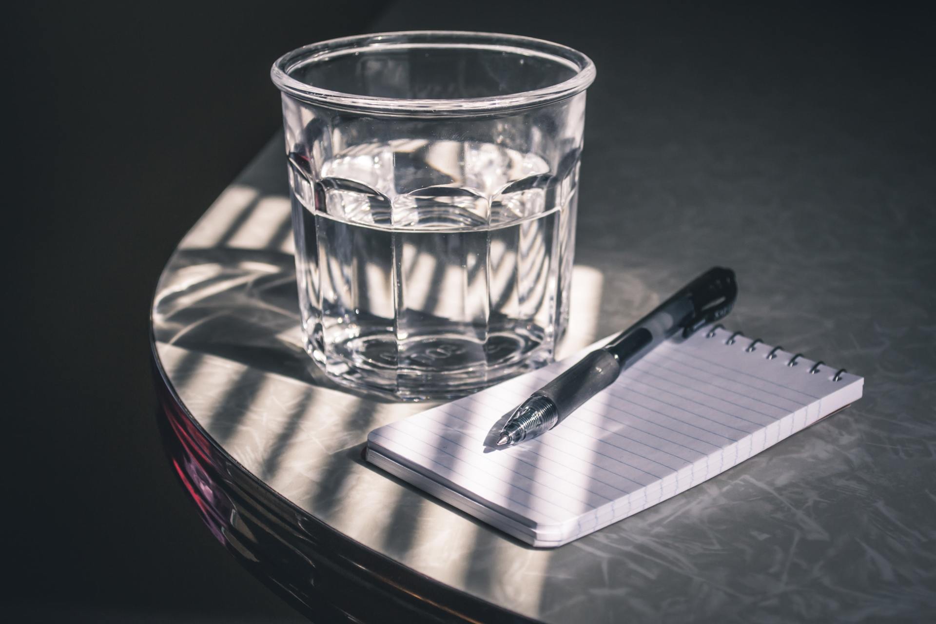 Bilde av et glass med vann, og penn og papir, mot munntørrhet ved Smil Tannlegesenter Bilde av et glass med vann, og penn og papir, mot munntørrhet ved Smil Tannlegesenter
