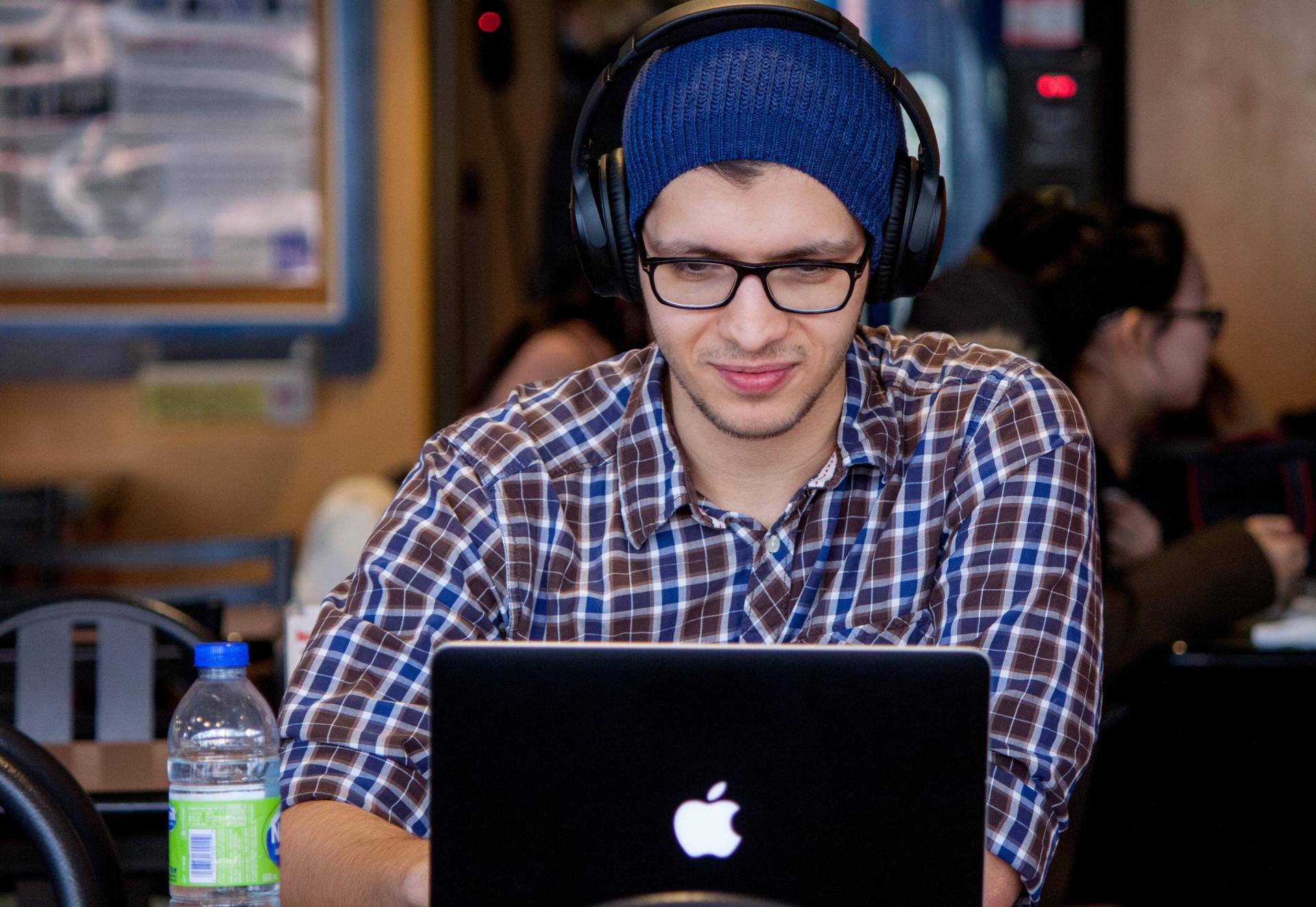A man wearing headphones is using an apple laptop