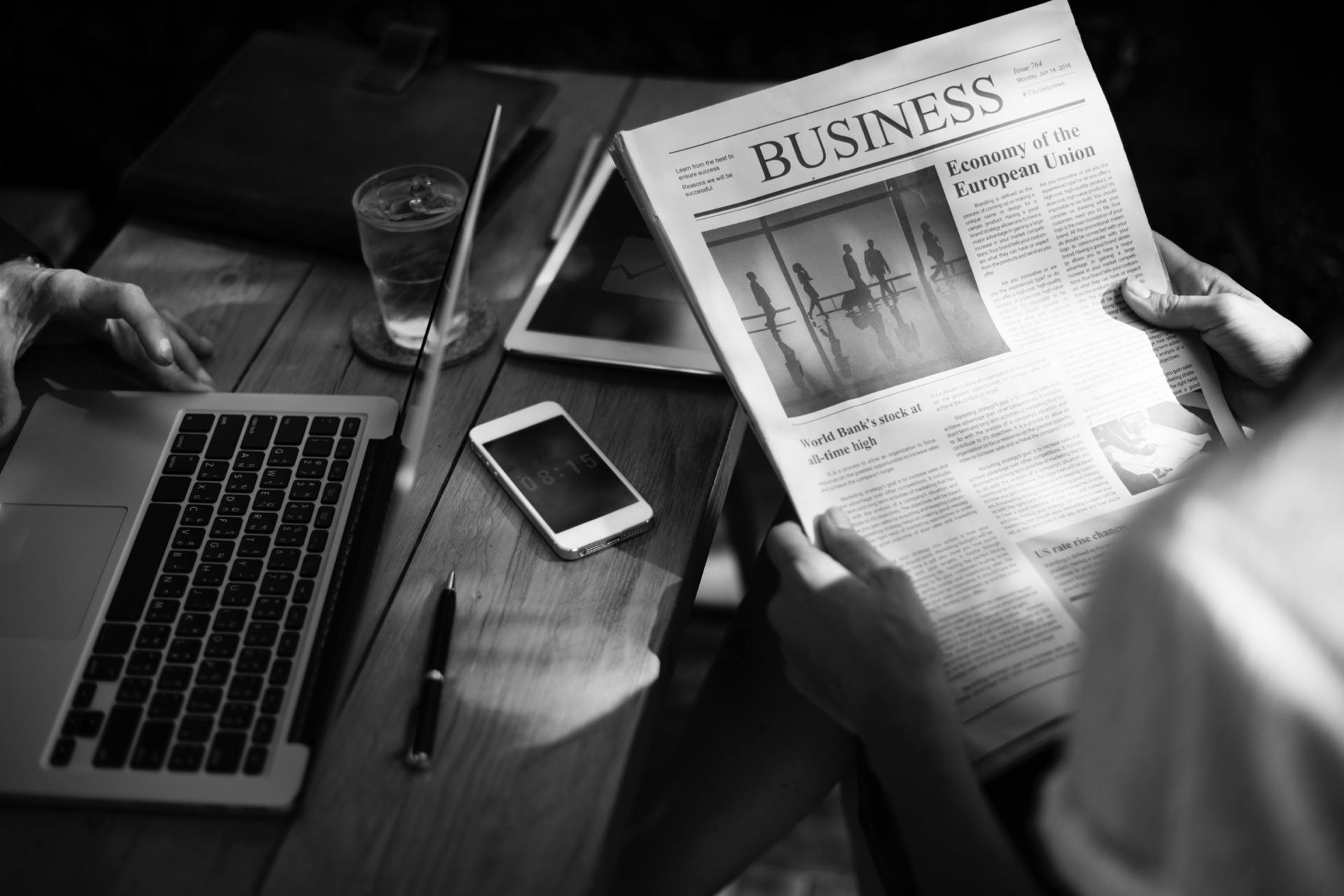 A person is sitting at a table reading a newspaper.