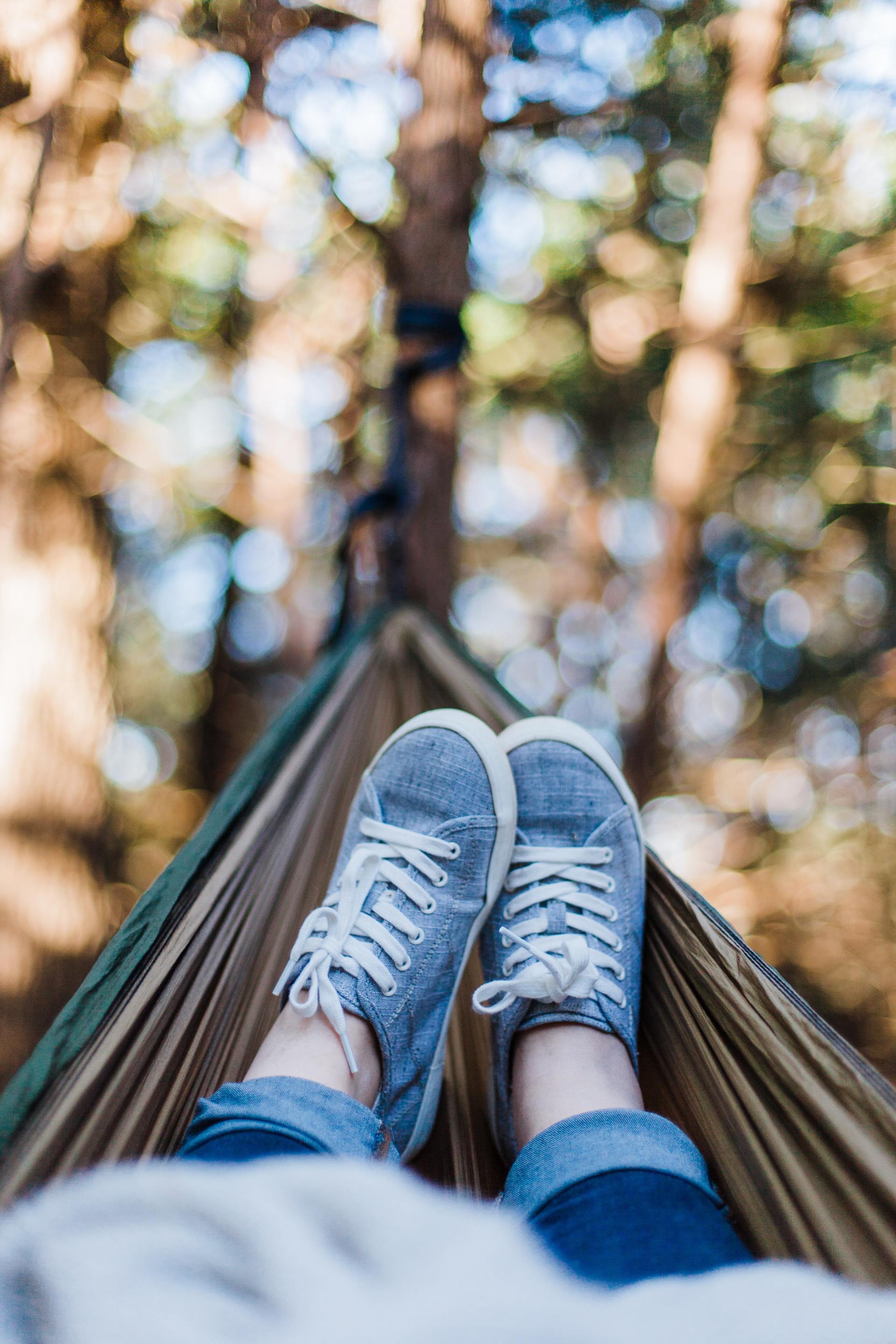 Blue sneakers in a hammock with blurred trees in the background