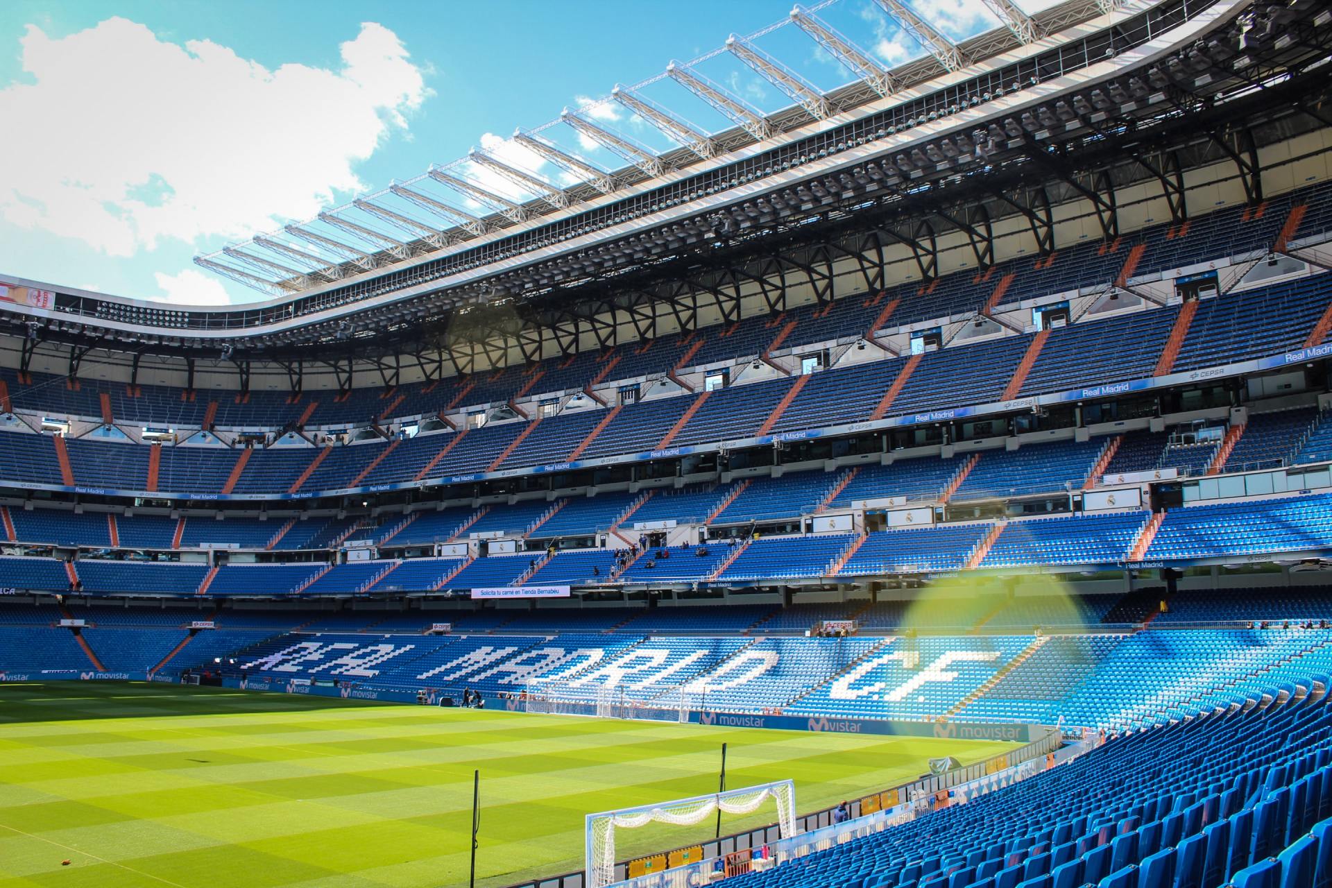 An empty soccer stadium with blue seats and a goal.
