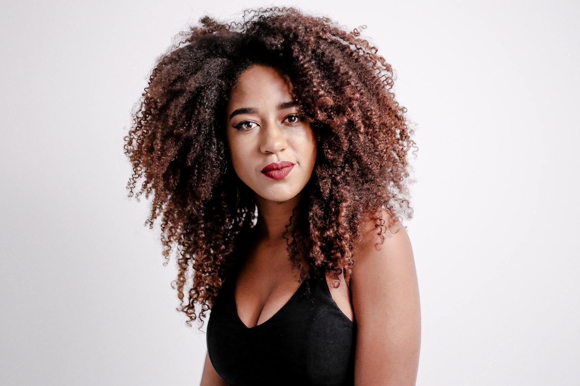 A woman with curly hair is wearing a black tank top.