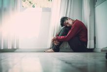 Young man sitting on floor and hugging his knees