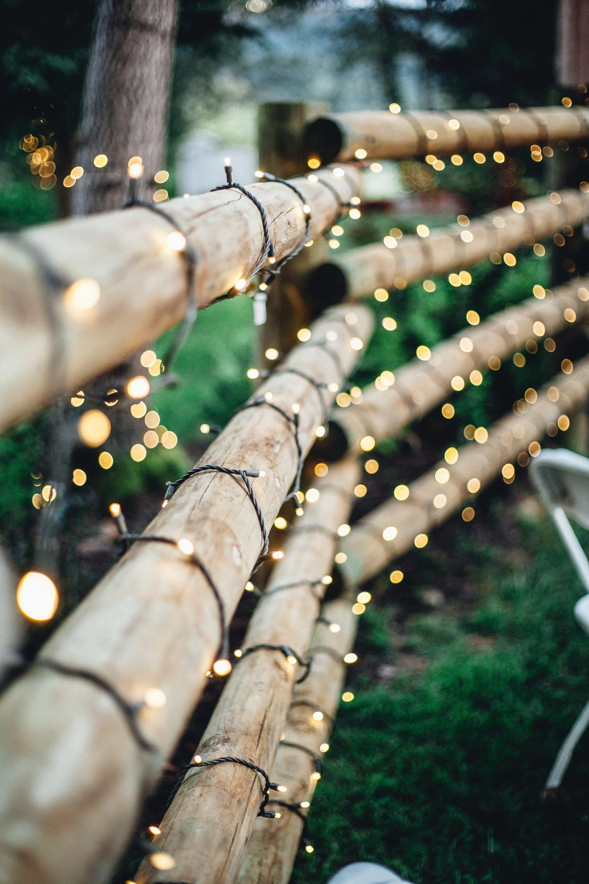 A wooden fence with christmas lights hanging from it.