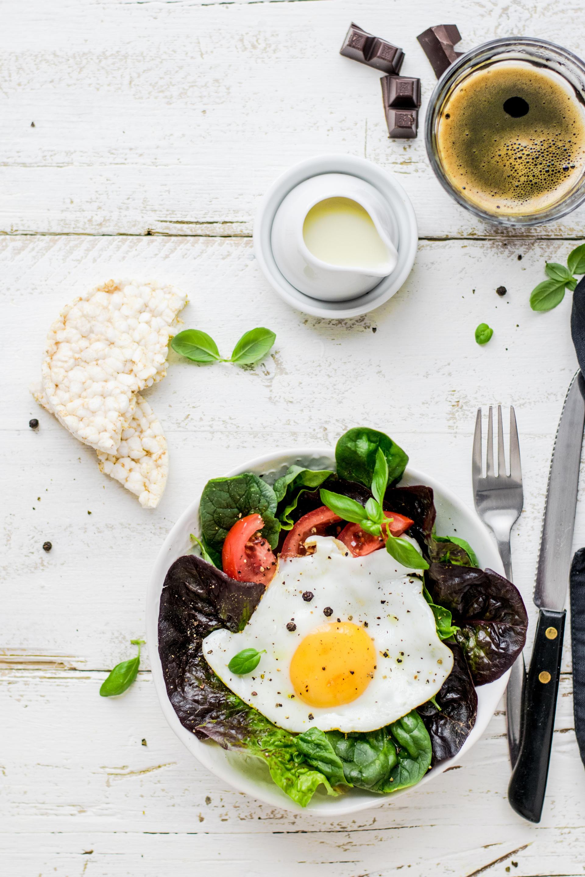 A bowl of salad with a fried egg on top of it.
