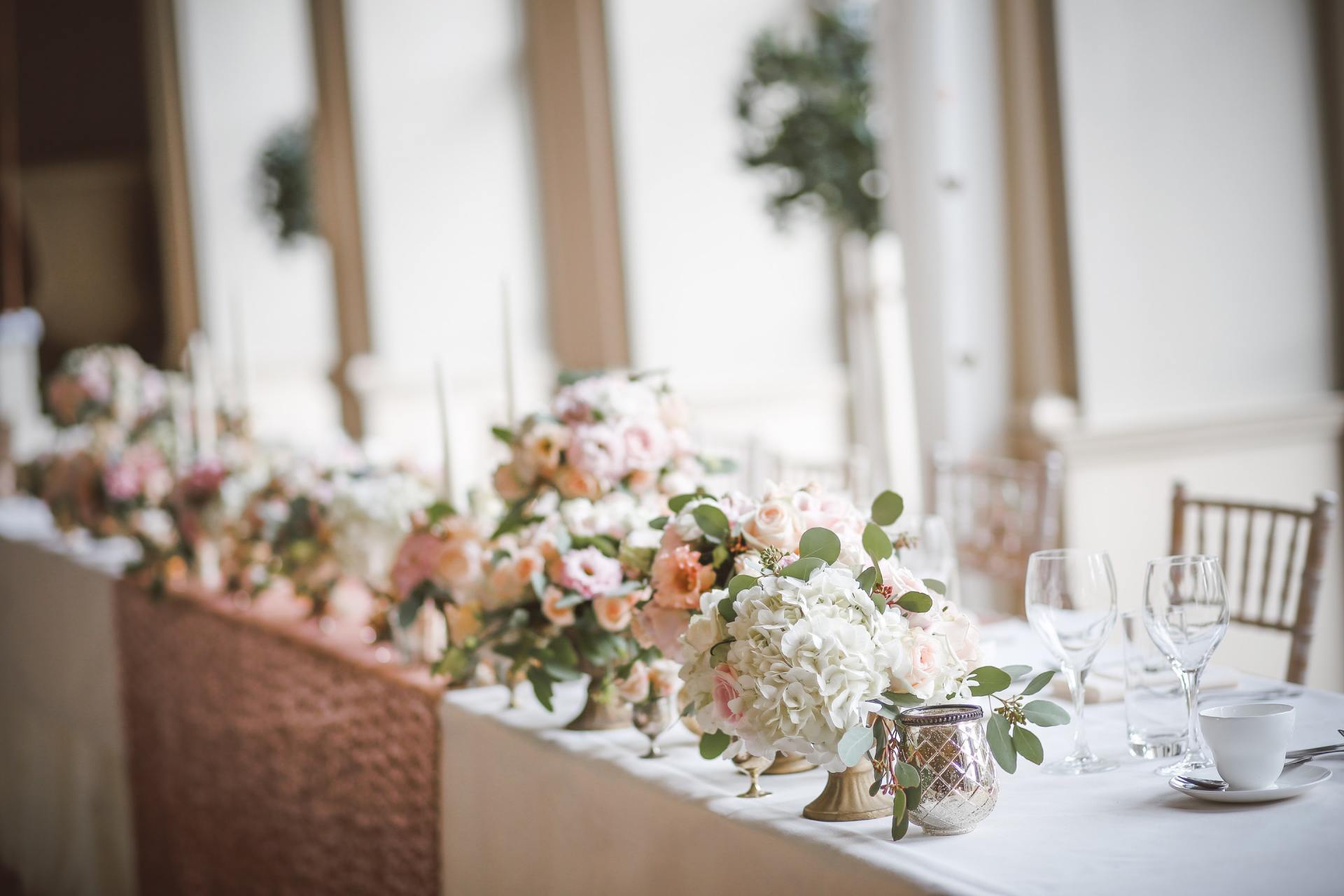 Wedding reception table with floral arrangements and glassware.