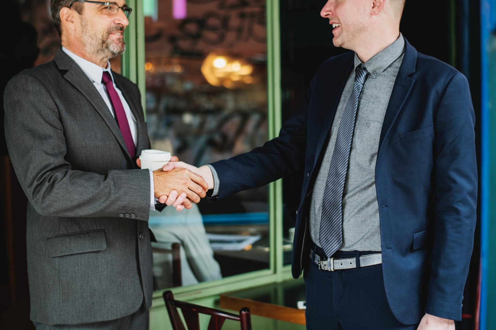 Two businessmen shaking hands in a modern office lobby