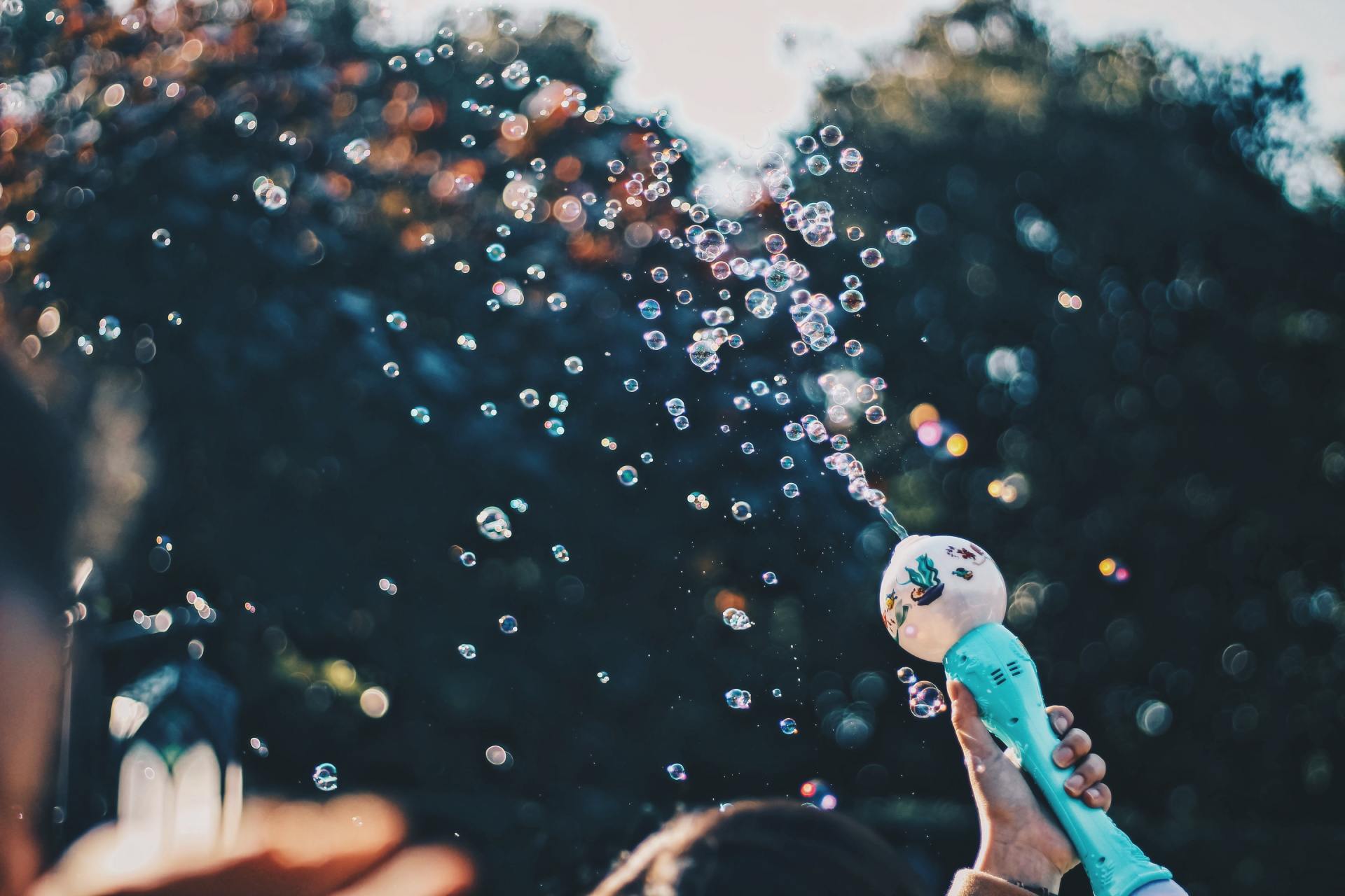 A person is blowing soap bubbles with a soap dispenser