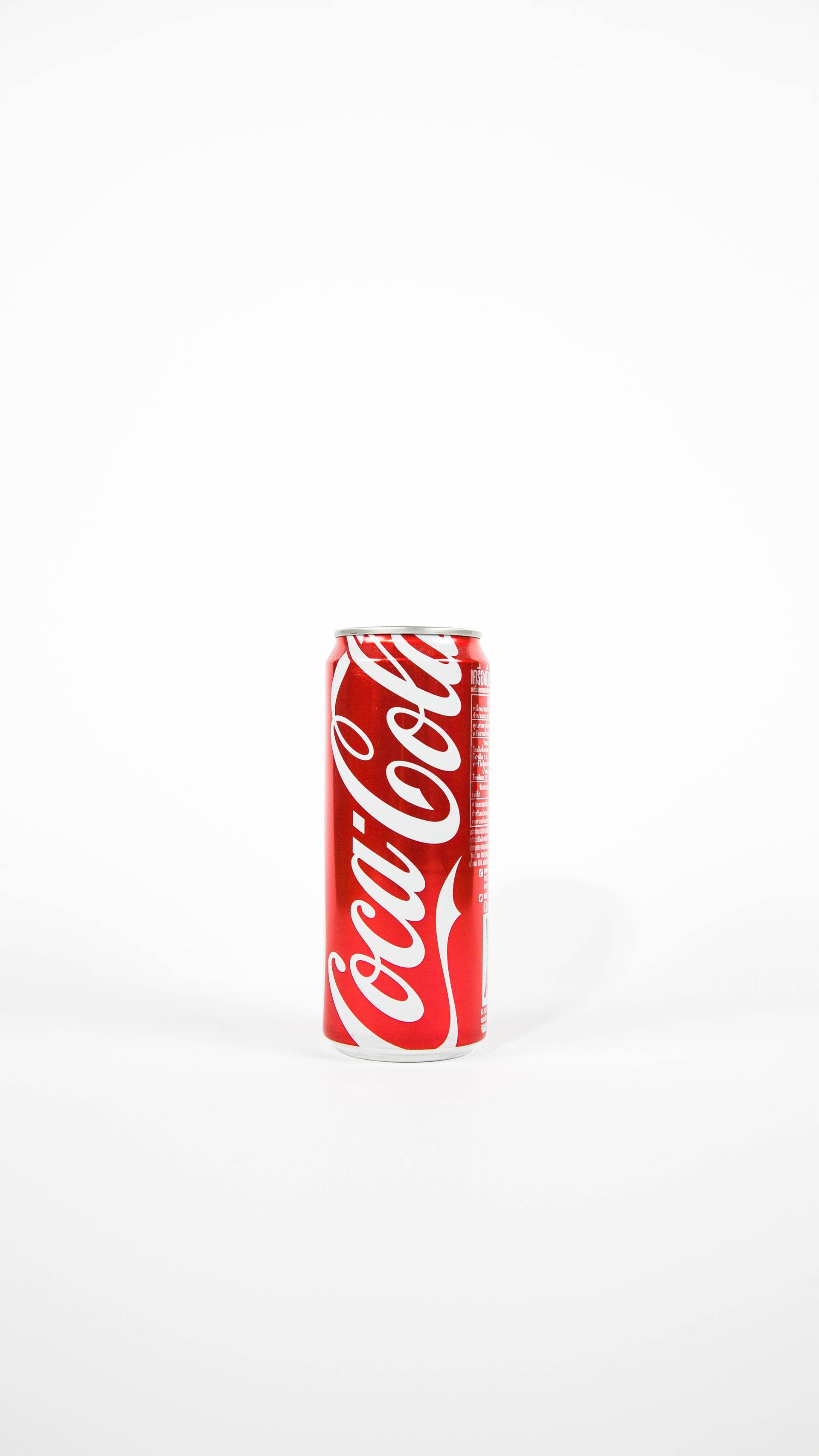 A can of coca cola is sitting on a white surface.