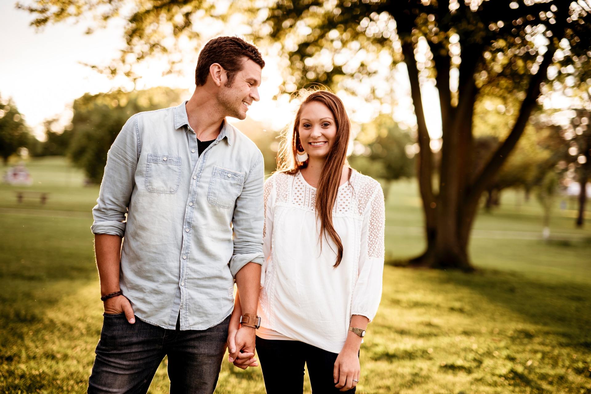 A man and a woman are holding hands in a park.