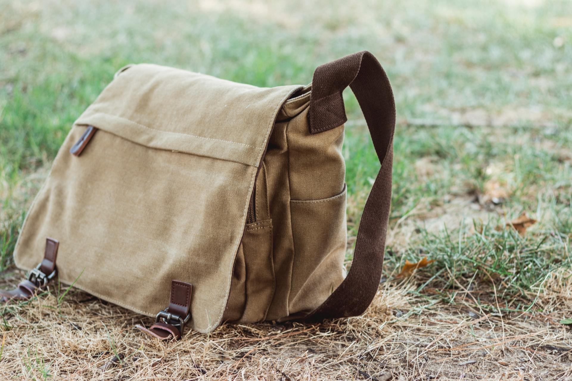 Hellbrauner Canvas-Rucksack auf trockenem Gras mit braunen Riemen und Schnallen