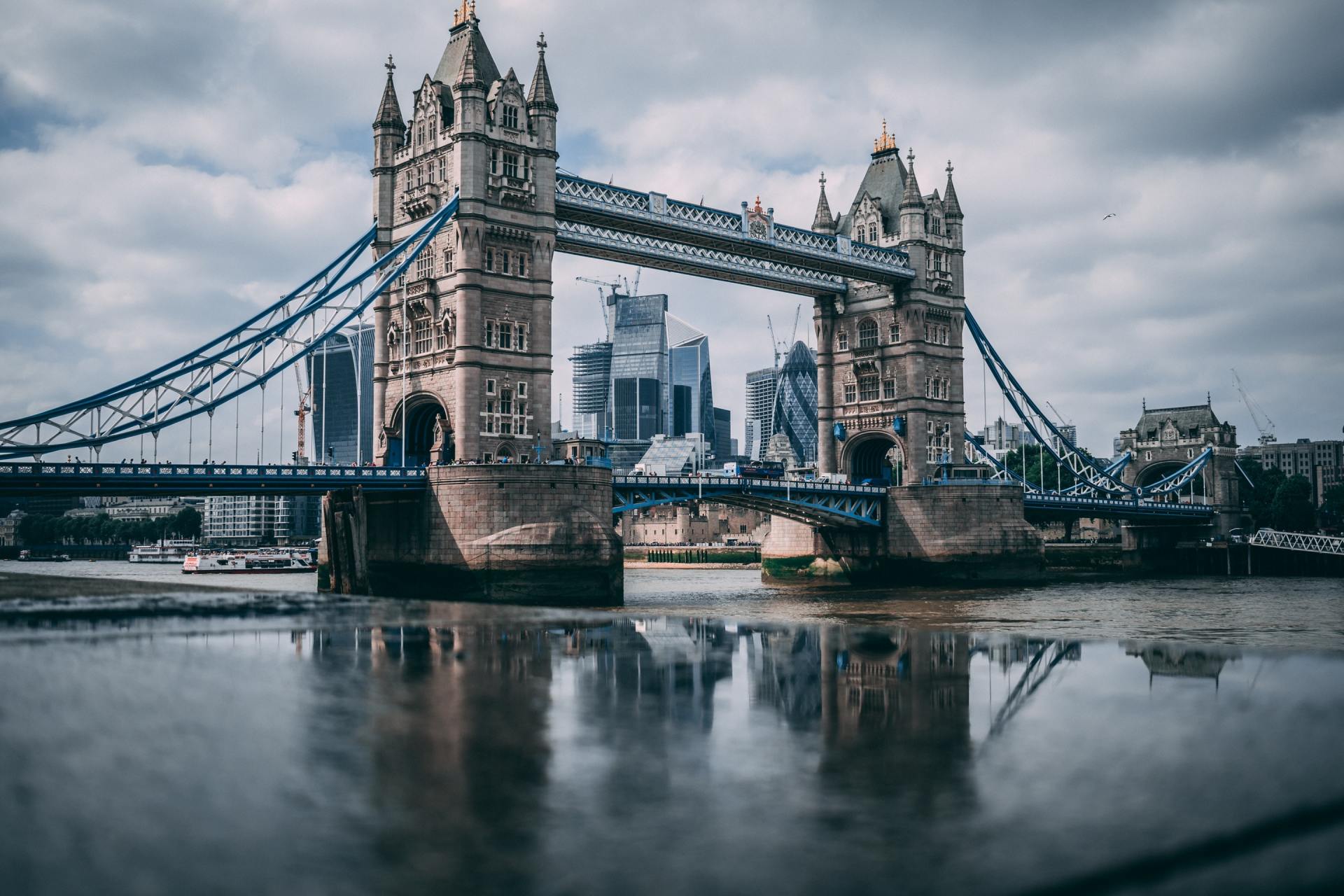 The tower bridge in london is reflected in the water.