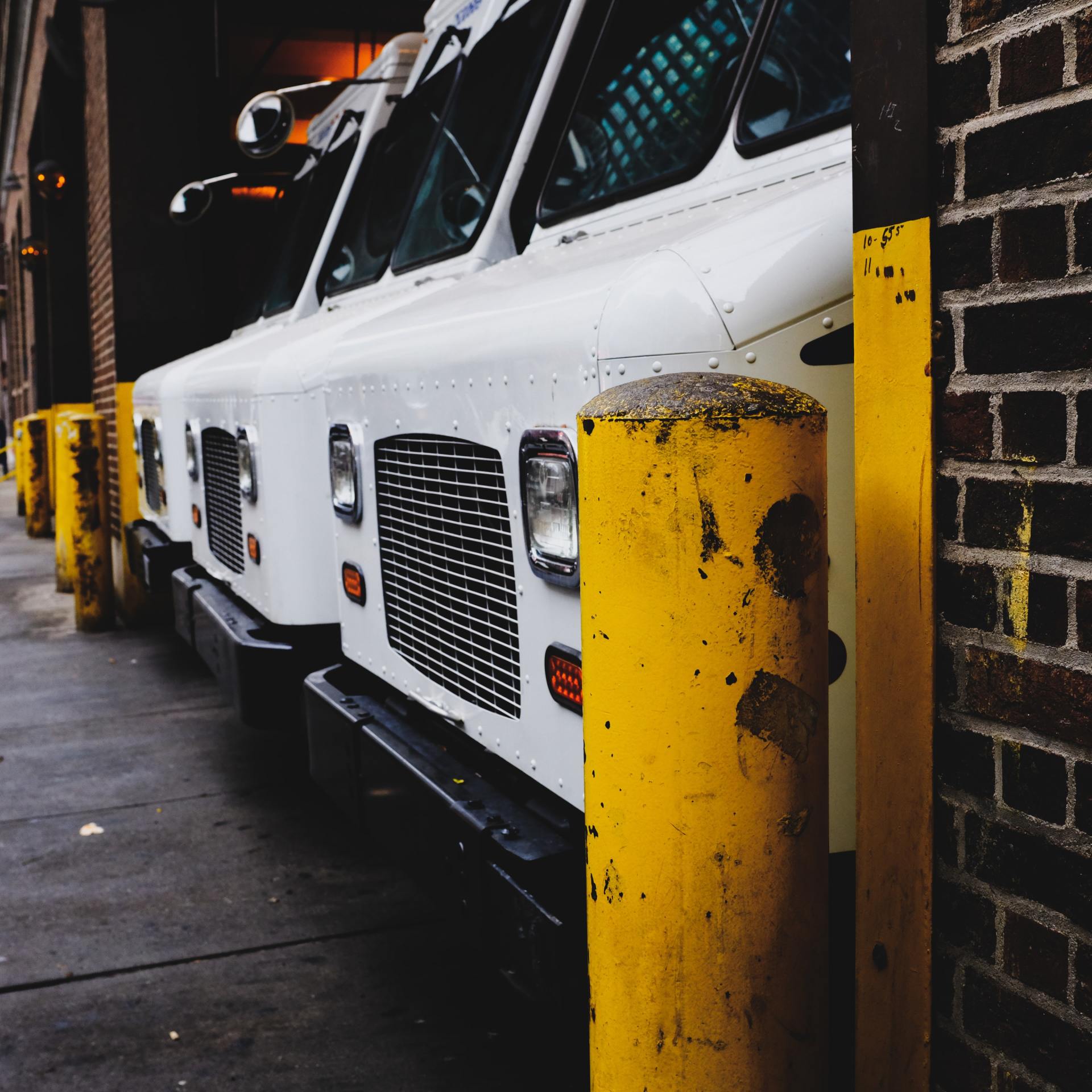 A row of white trucks parked next to a yellow pole