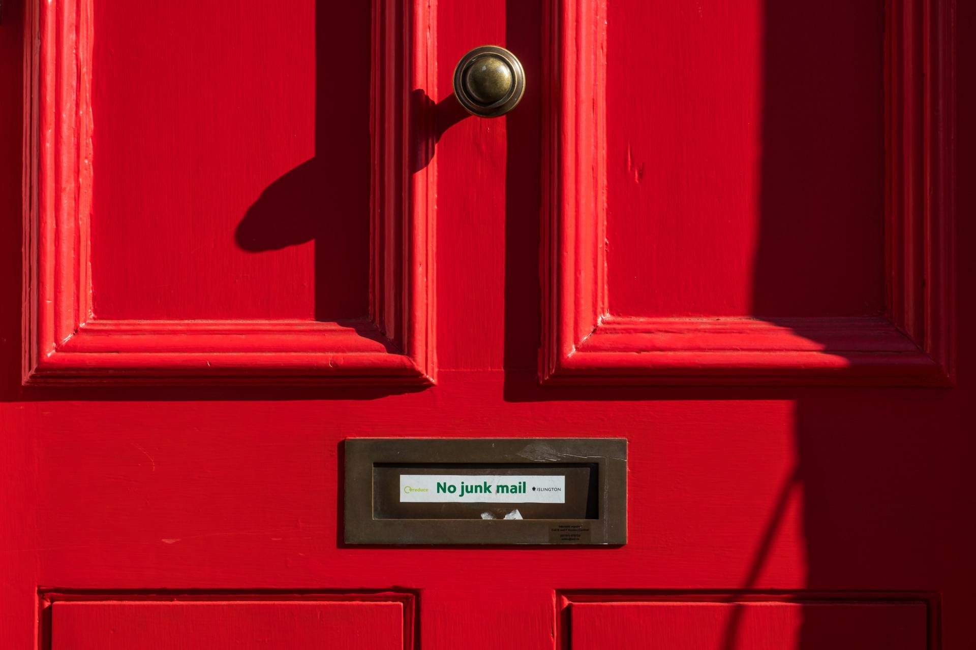 Red door with a brass doorknob and a mailbox slot. The word 