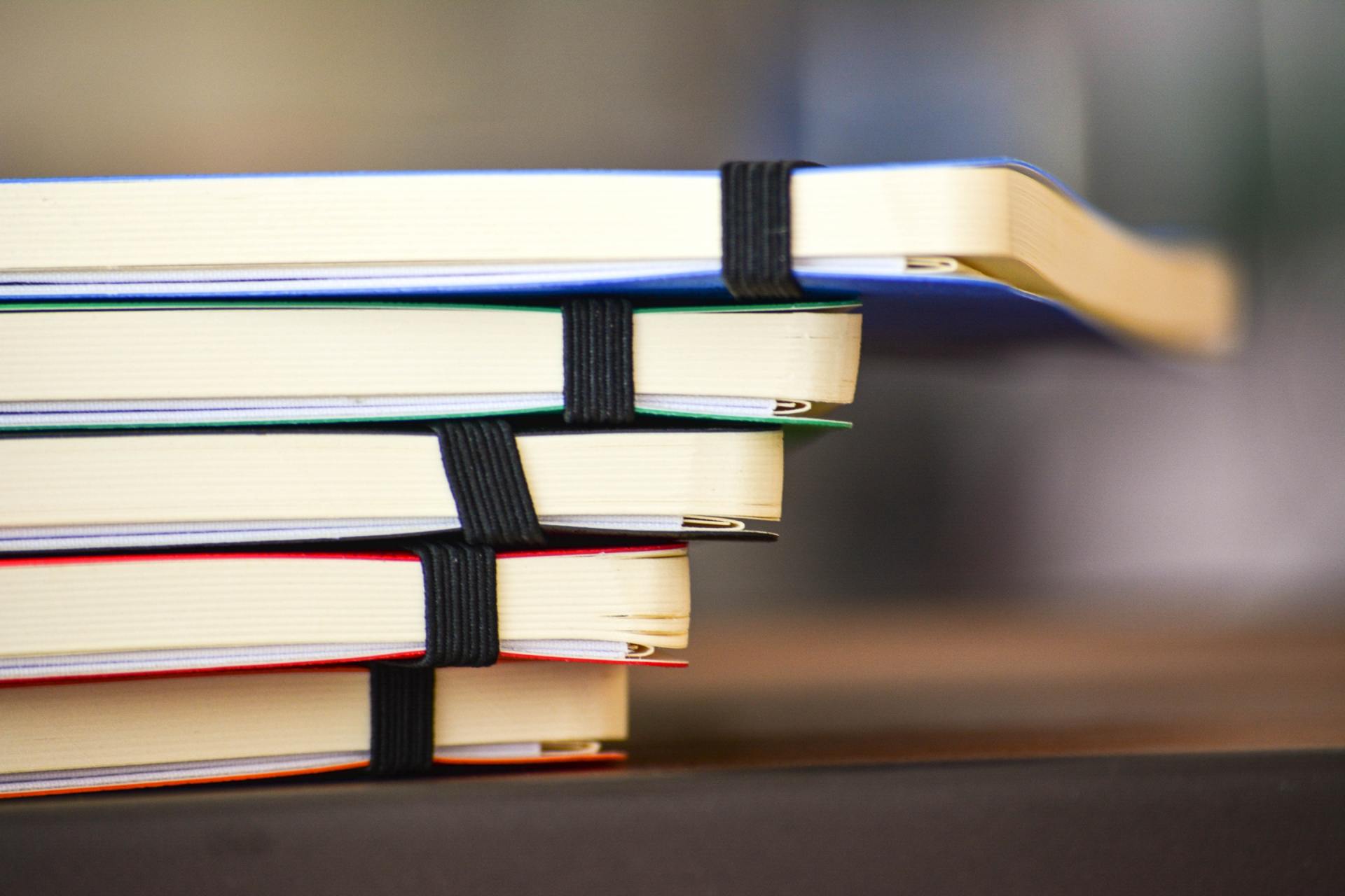 Four notebooks are stacked on top of each other on a table