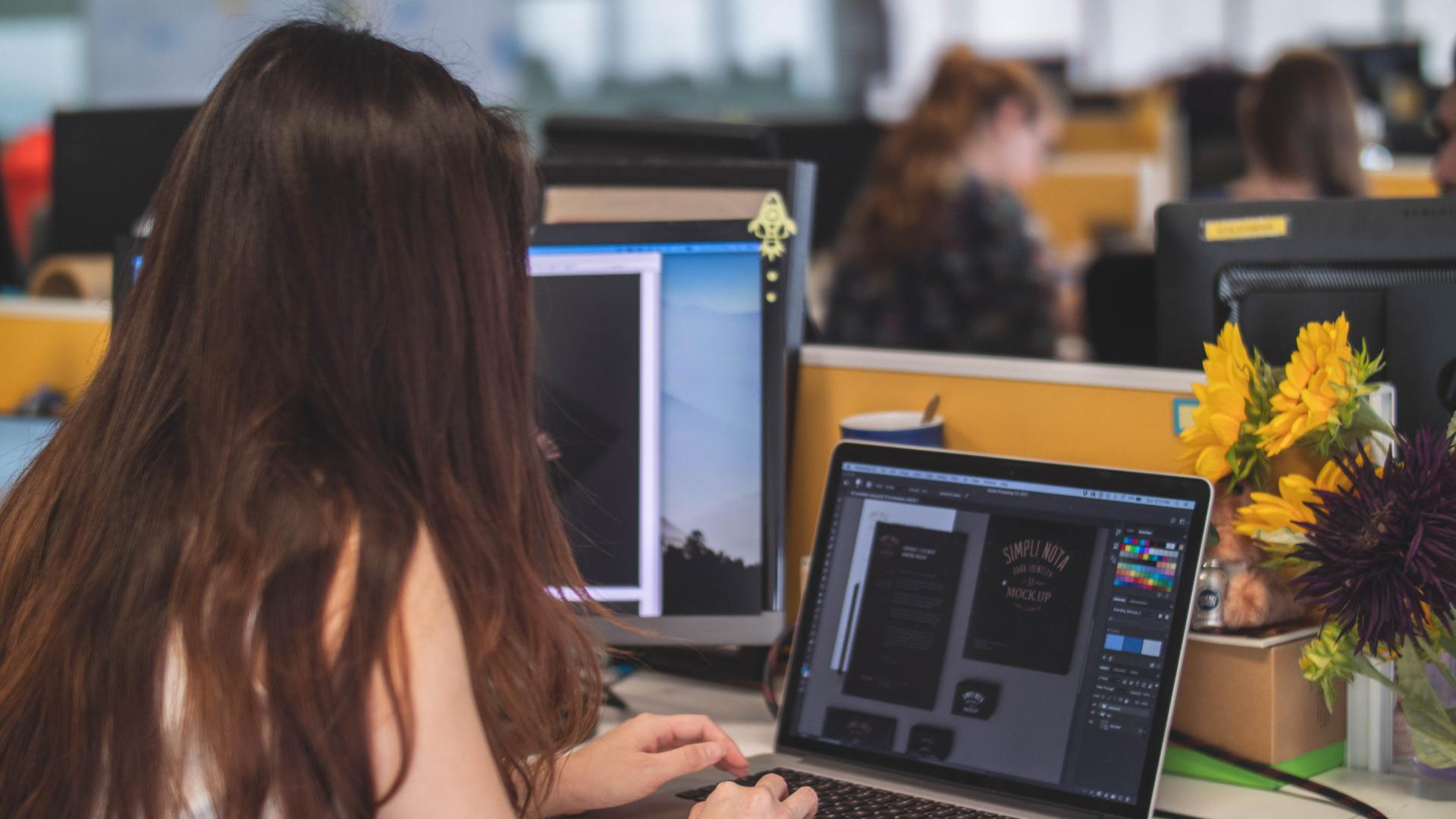 A woman is sitting at a desk using a laptop computer.