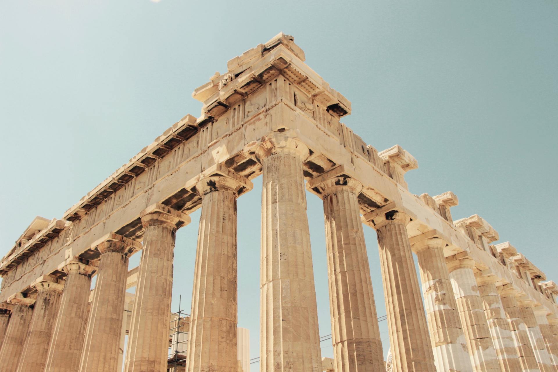 Looking up at a row of columns against a blue sky.