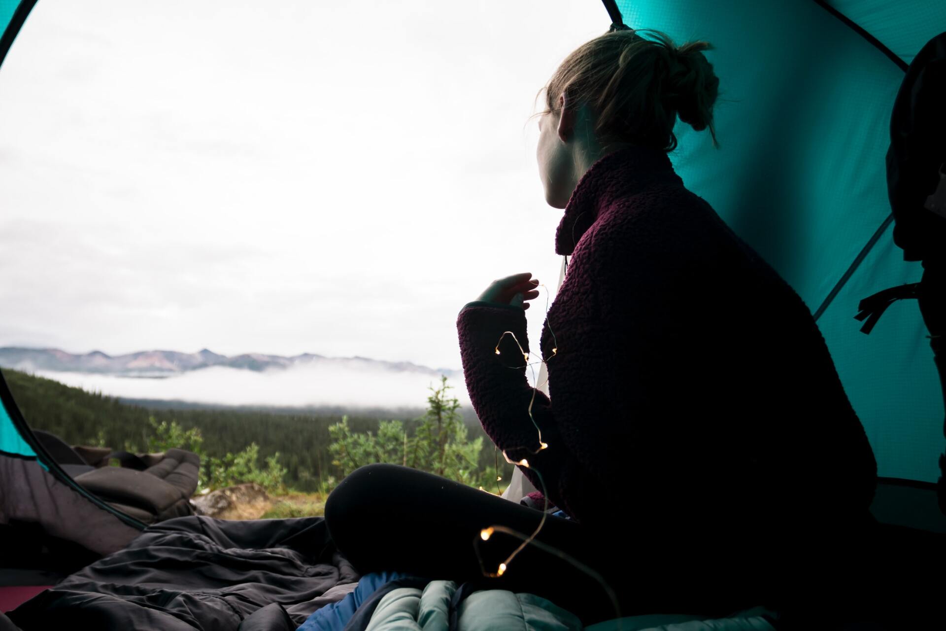 a woman is sitting in a tent looking out the window .