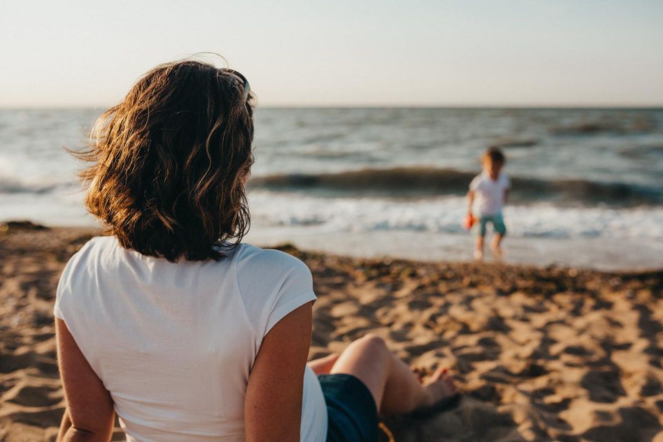 Woman watching child play at the beach