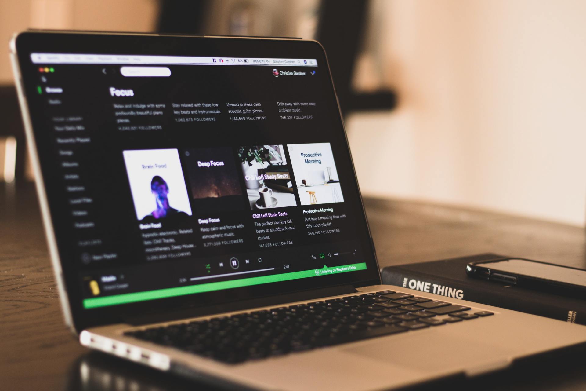 A laptop is open to spotify on a table.